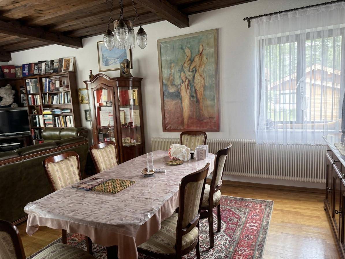 Traditioneller Essbereich mit Holzbalkendecke, großem Esstisch und einem farbenfrohen Teppich.
