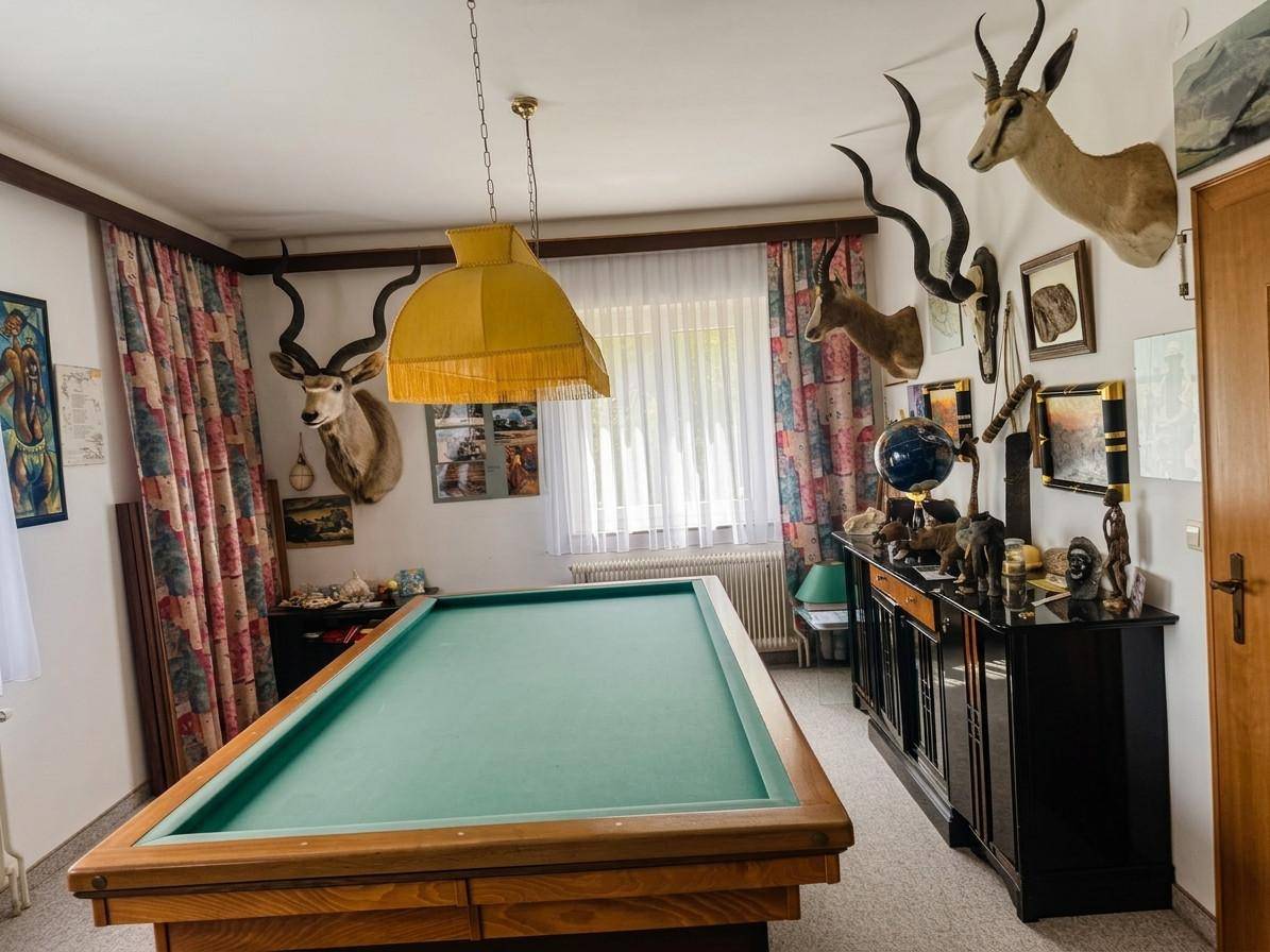 Spielzimmer mit Billardtisch, Jagdtrophäen an den Wänden und farbenfrohen Vorhängen.