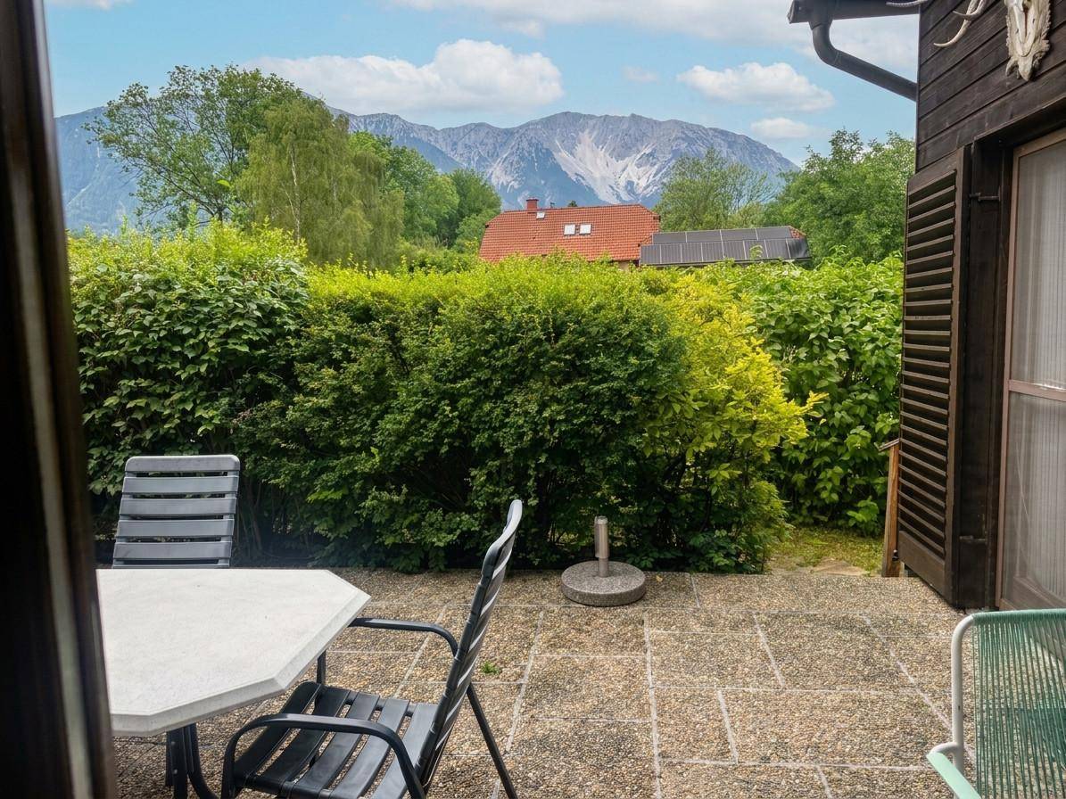Gemütliche Terrasse mit Gartenmöbeln und beeindruckendem Bergblick, umgeben von grünen Hecken.