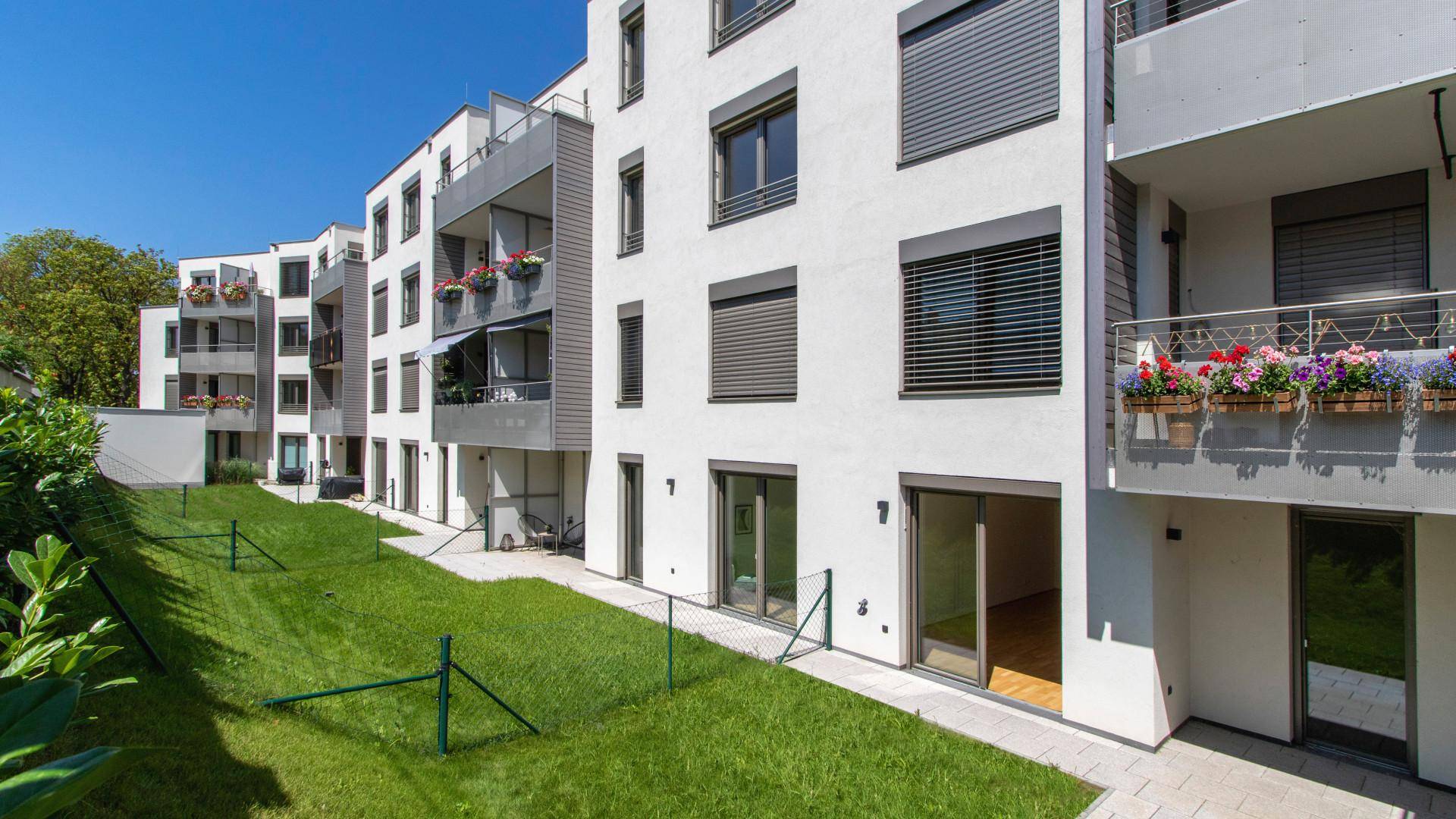 Moderne Wohnanlage bei Tag mit grünen Rasenflächen und Balkonen.