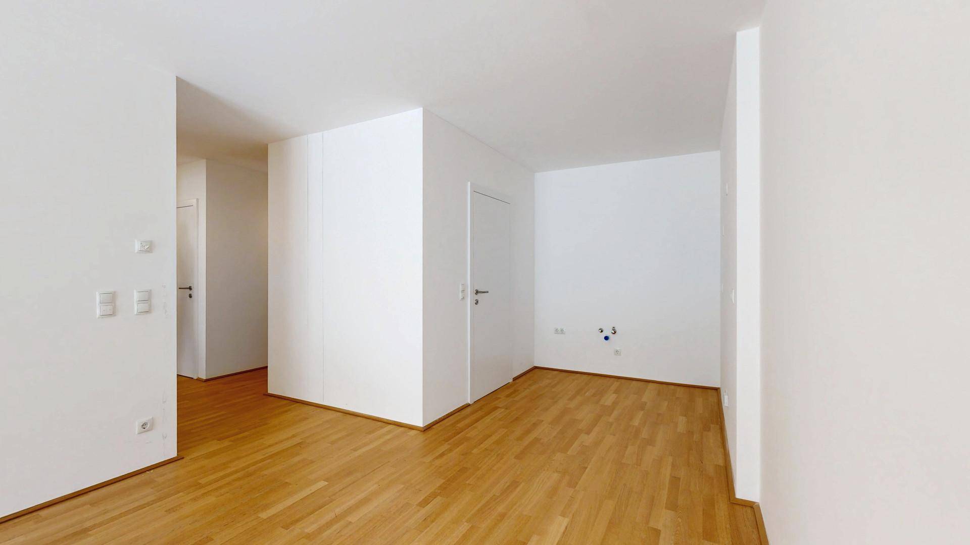 Leerer Raum mit Holzboden und weißen Wänden, bietet flexible Gestaltungsmöglichkeiten.