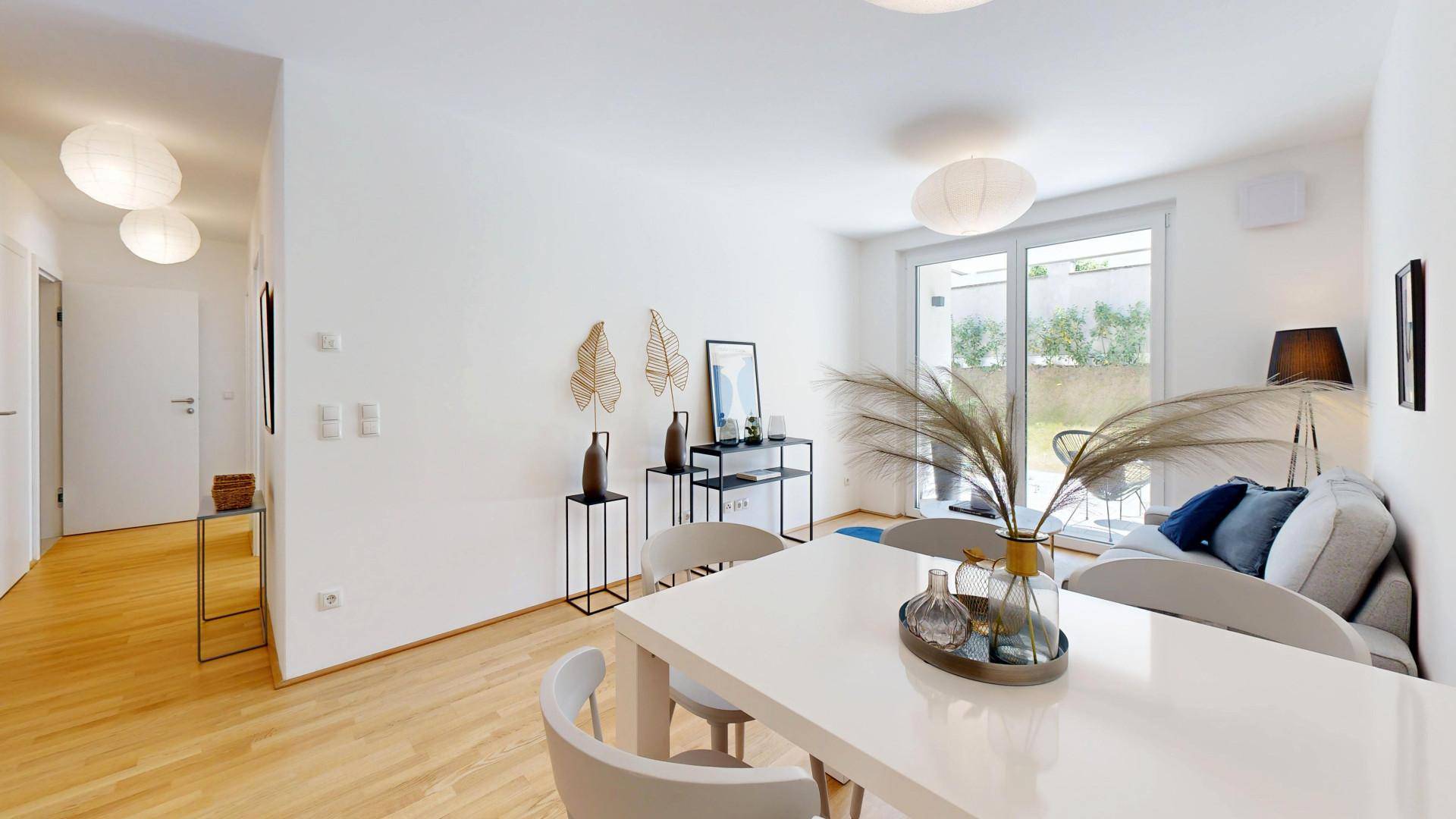 Lichtdurchfluteter Wohnbereich mit Zugang zur Terrasse und modernem Mobiliar.
