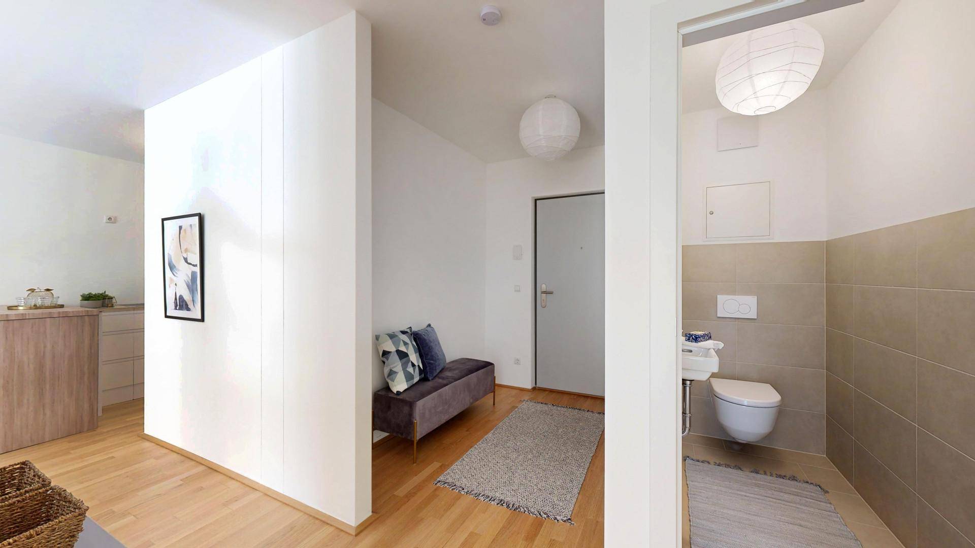 Eingangsbereich mit Sitzbank und Blick in ein separates Gäste-WC.
