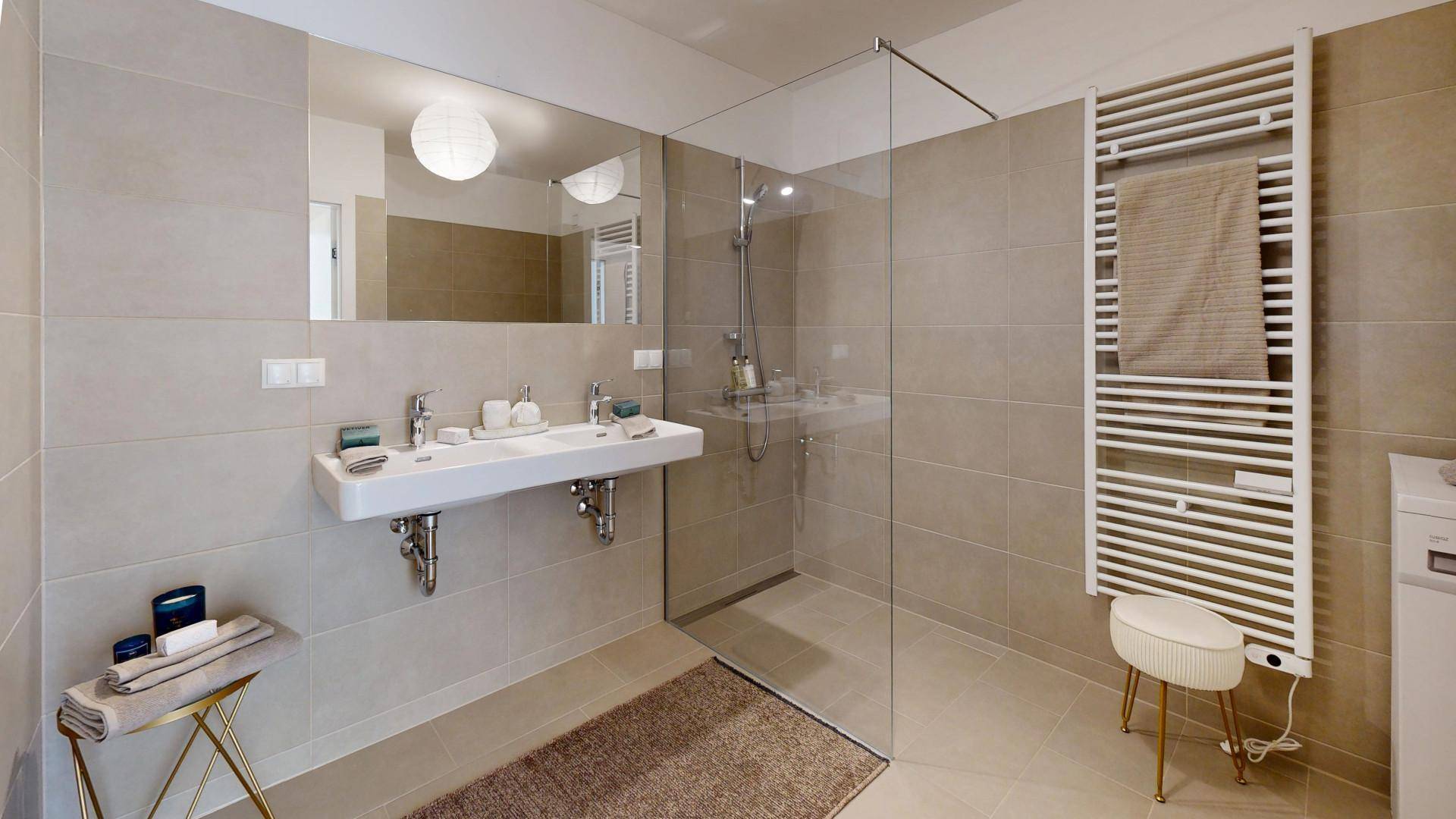 Modernes Badezimmer mit Doppelwaschbecken, ebenerdiger Dusche und Handtuchheizkörper.