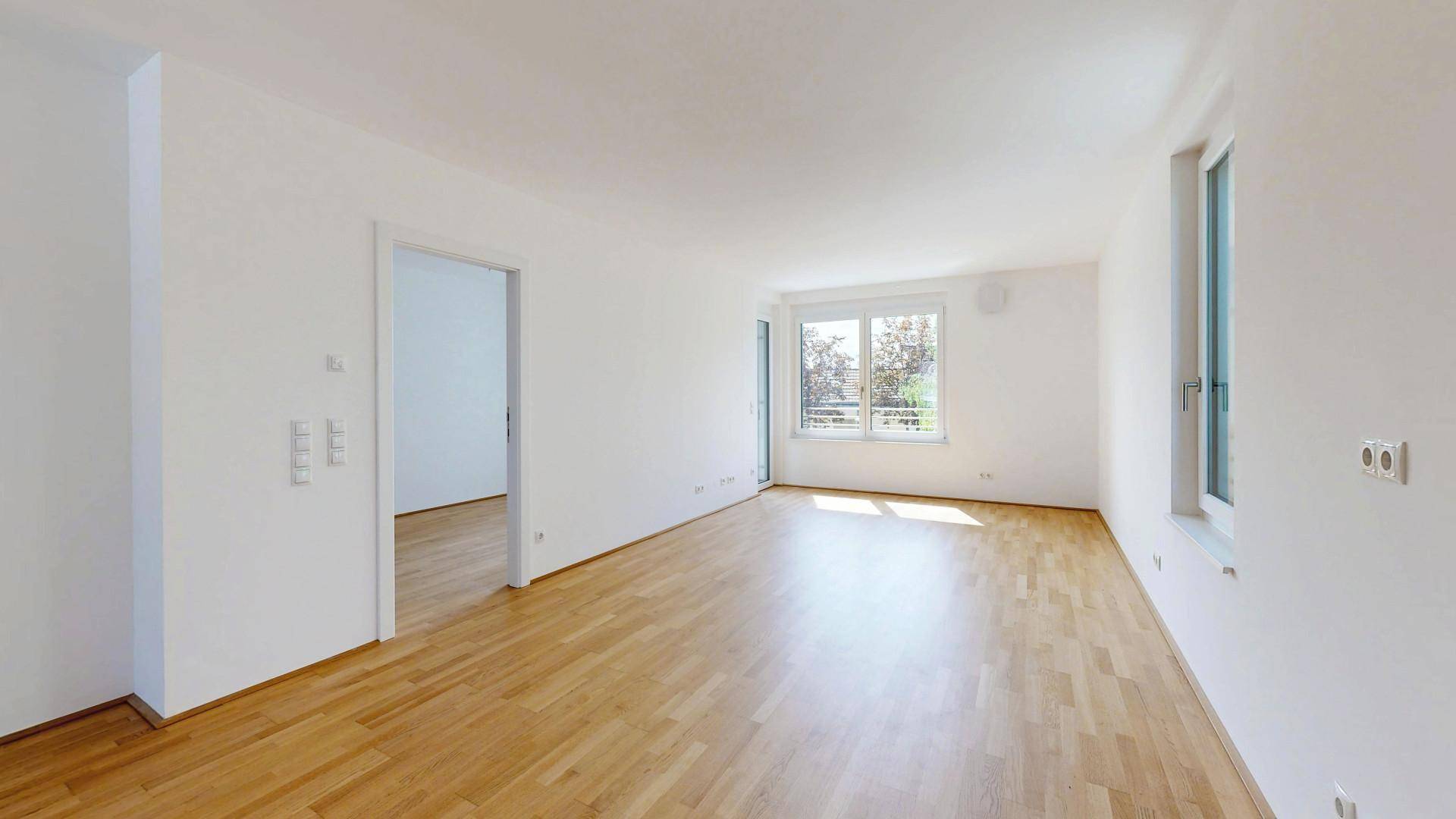 Geräumiges, helles Zimmer mit Parkettboden und großen Fenstern, bietet viel Tageslicht.