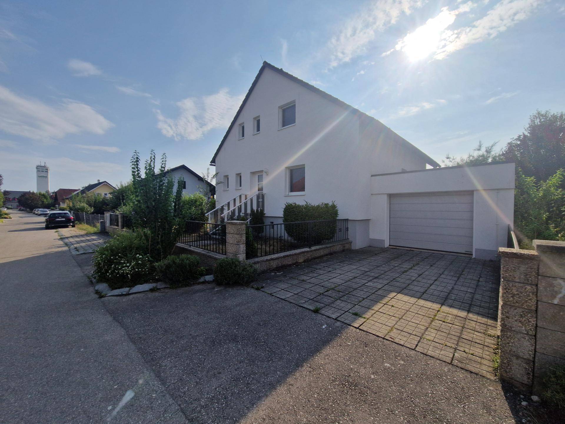 Vorderansicht des Hauses mit integrierter Garage und gepflasterter Einfahrt.