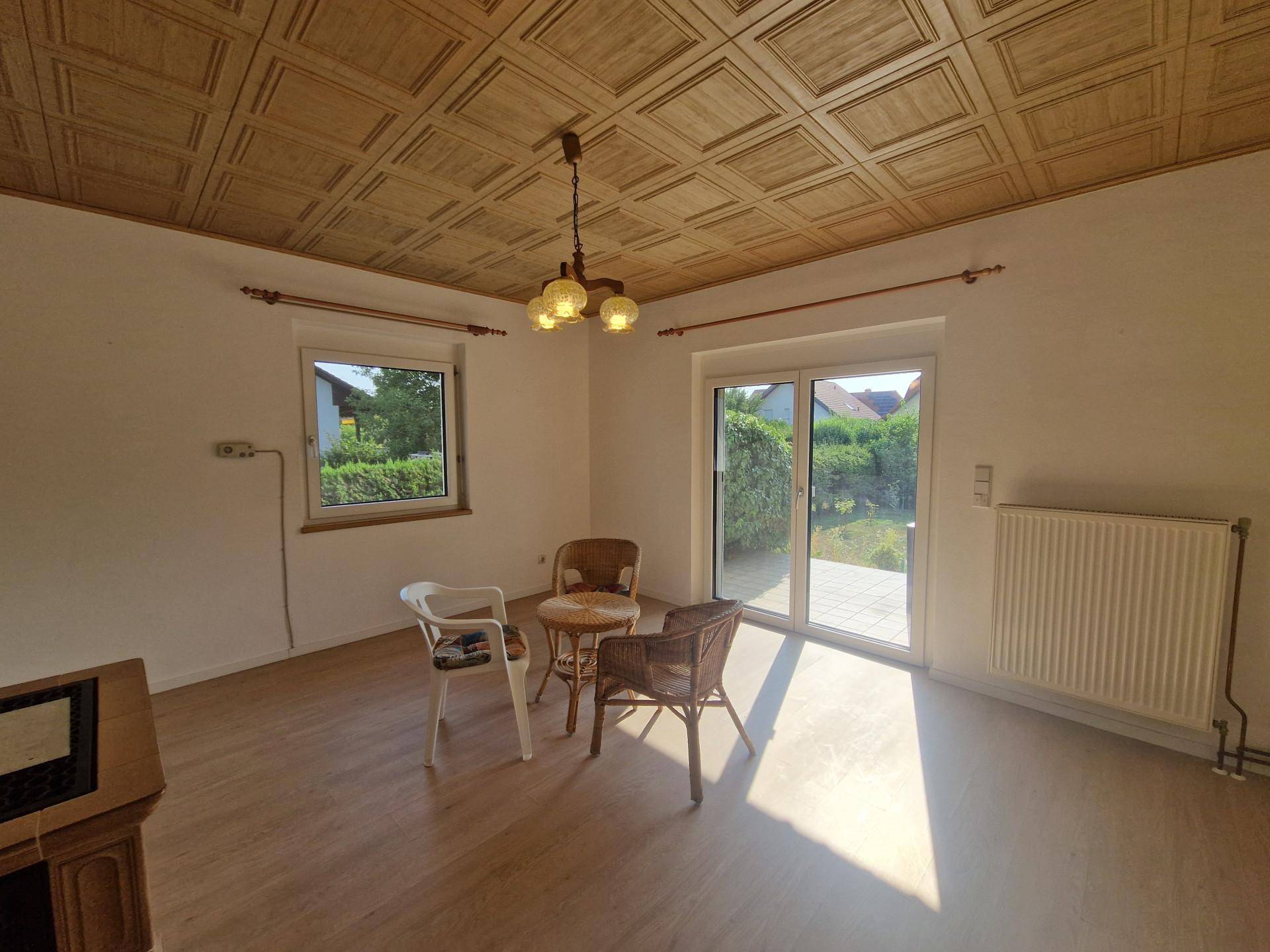 Helles Wohnzimmer mit Holzkassettendecke, Laminatboden und Zugang zum Garten.