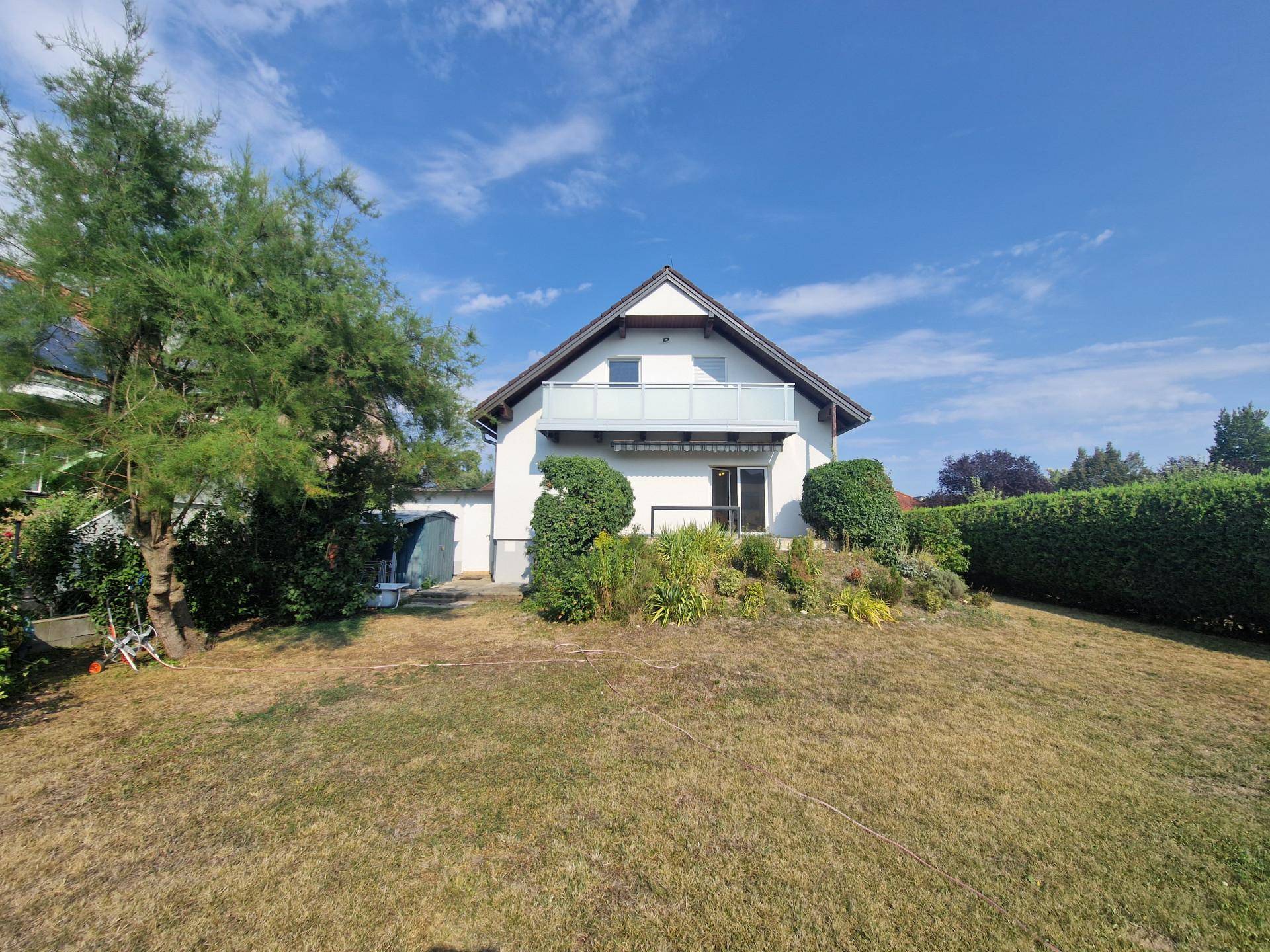 Rückansicht des Hauses mit Balkon im Obergeschoss und großem Garten.
