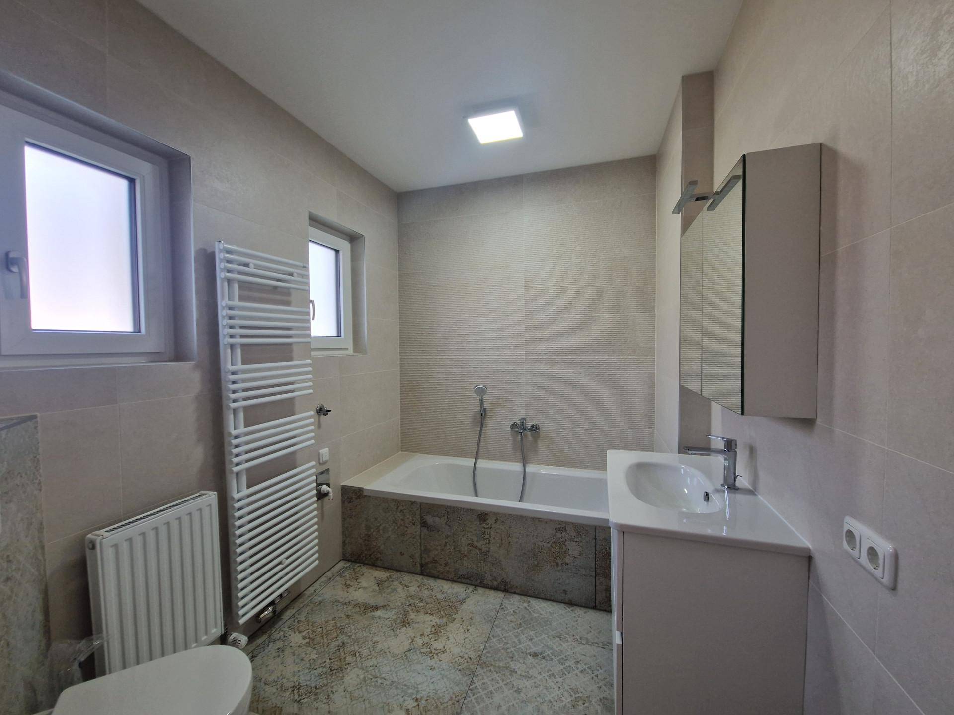 Modernes Badezimmer mit Badewanne, Waschtisch und beheiztem Handtuchhalter.