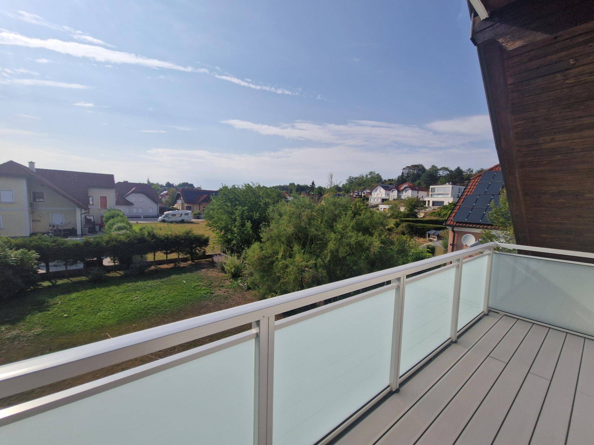 Balkon mit moderner Verglasung und weitem Blick über die grüne Umgebung.