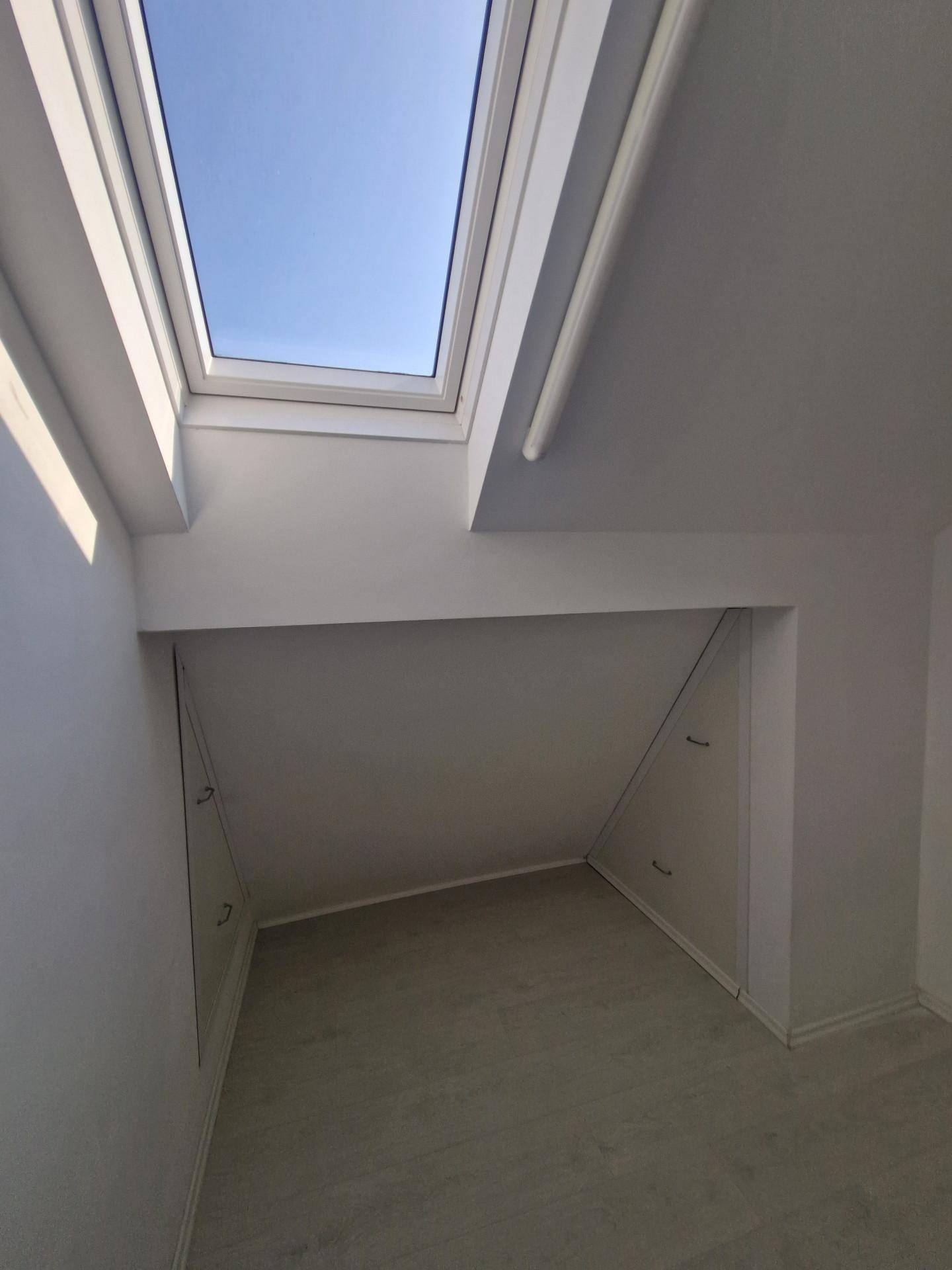 Heller Dachbodenraum mit Dachfenster und praktischen Einbauschränken.
