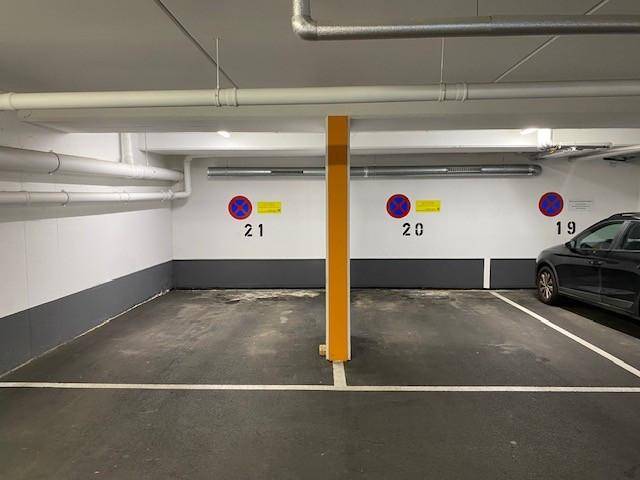 Tiefgarage mit markierten Stellplätzen und sichtbaren Versorgungsleitungen an der Decke.