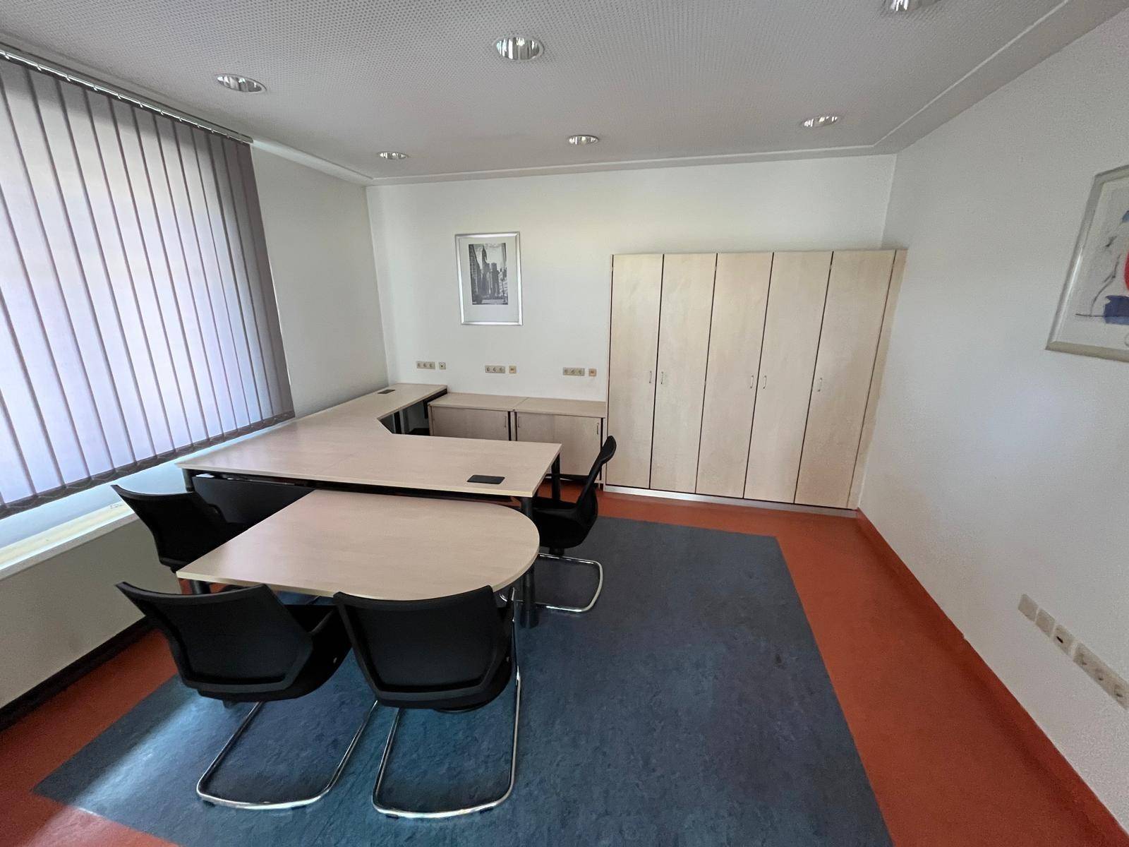 Geräumiges Büro mit mehreren Schreibtischen, Aktenschränken und großen Fenstern.