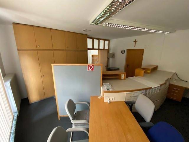Bürobereich mit Schreibtischen, Bürostühlen und integrierten Holzschränken, bereit für den Arbeitsalltag.