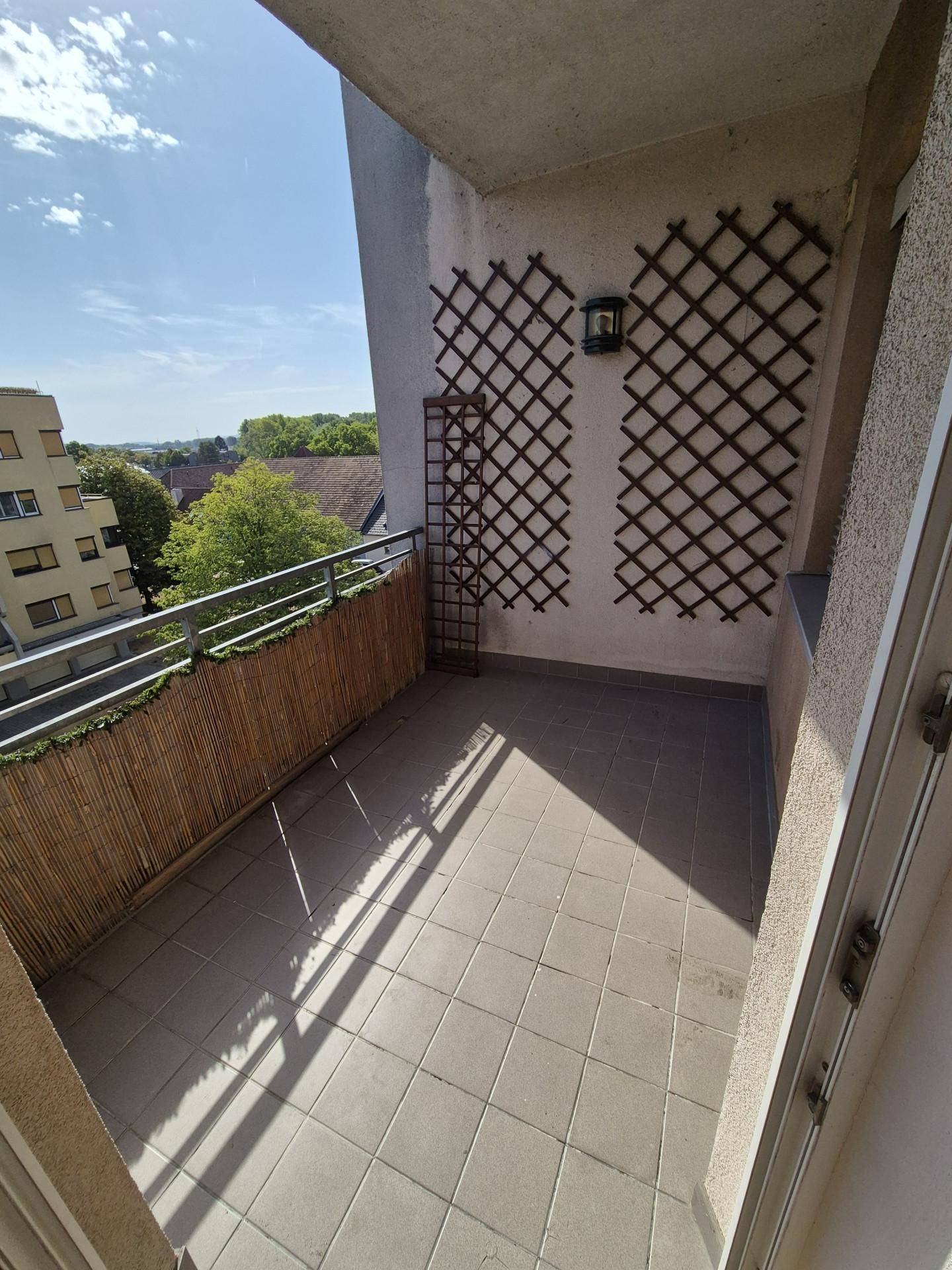 Sonniger Balkon mit Fliesenboden und Blick auf die umliegende Wohngegend.