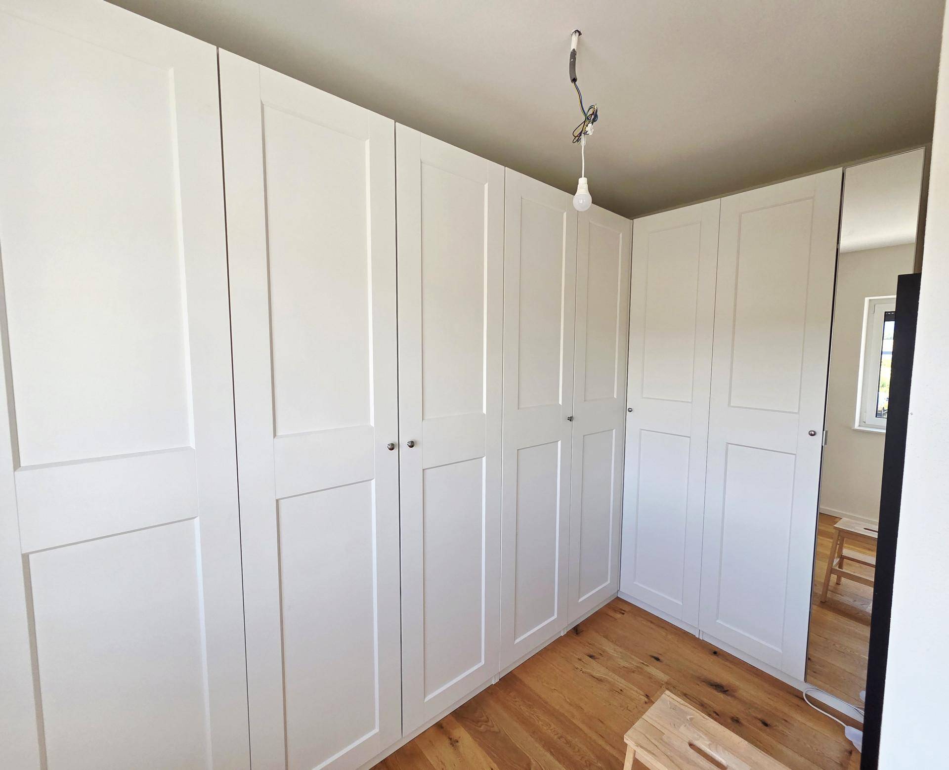 Schlafzimmer mit weißen Einbauschränken und Holzboden, bietet viel Stauraum.
