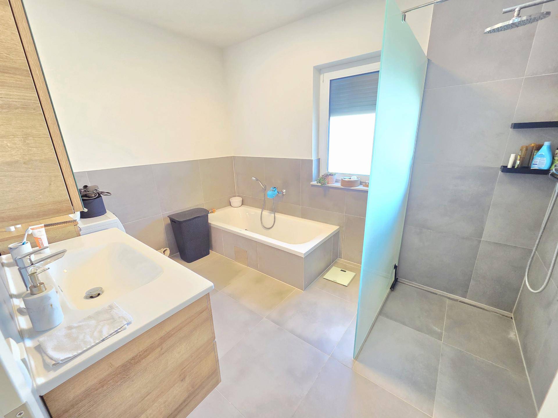 Modernes Badezimmer mit Badewanne, begehbarer Dusche und großformatigen Fliesen.