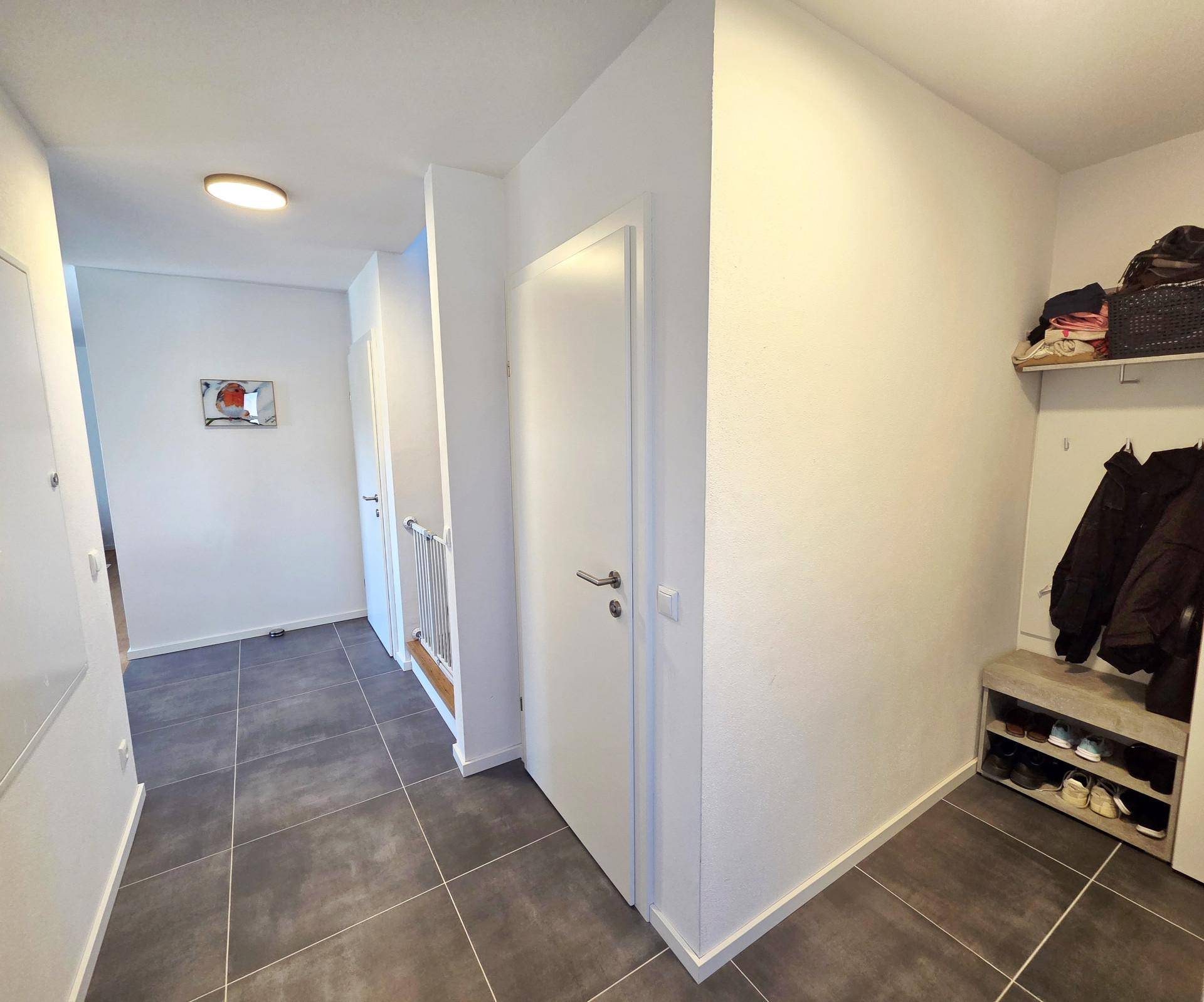 Geräumiger Flur mit Fliesenboden und Garderobe, der zu den weiteren Räumen führt.