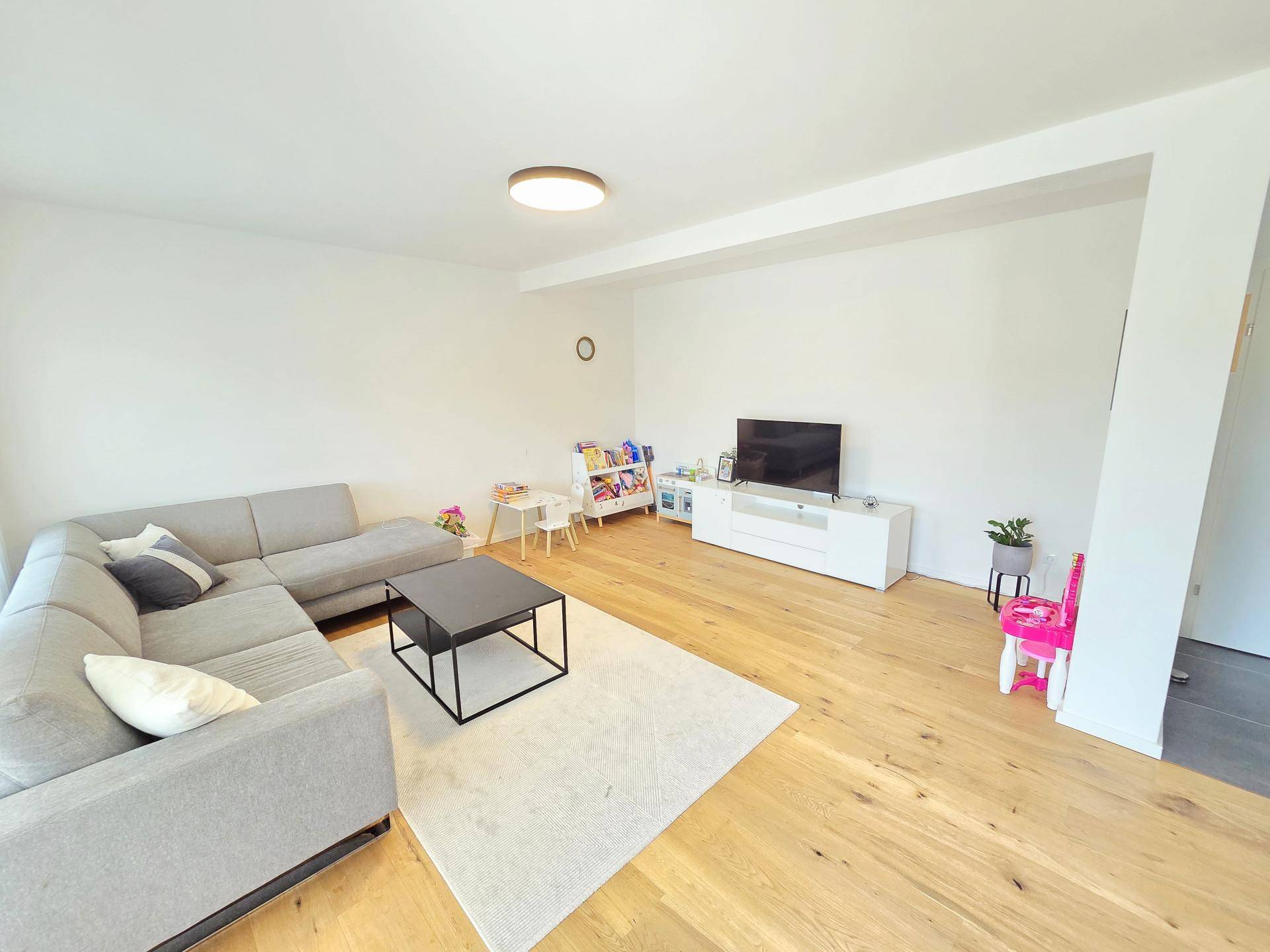 Geräumiges Wohnzimmer mit großem Ecksofa, Couchtisch und Fernseher, hell und modern.