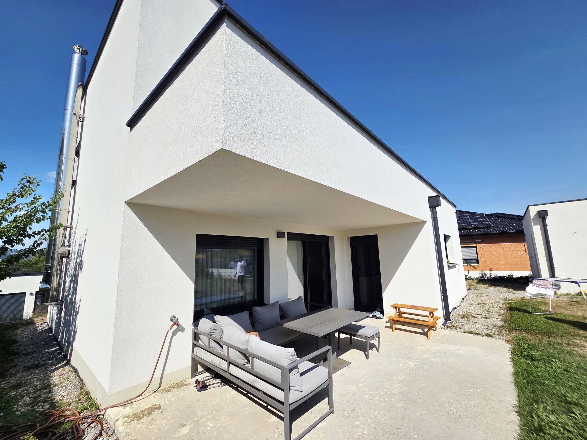 Überdachte Terrasse mit modernen Gartenmöbeln und Blick auf die Umgebung.
