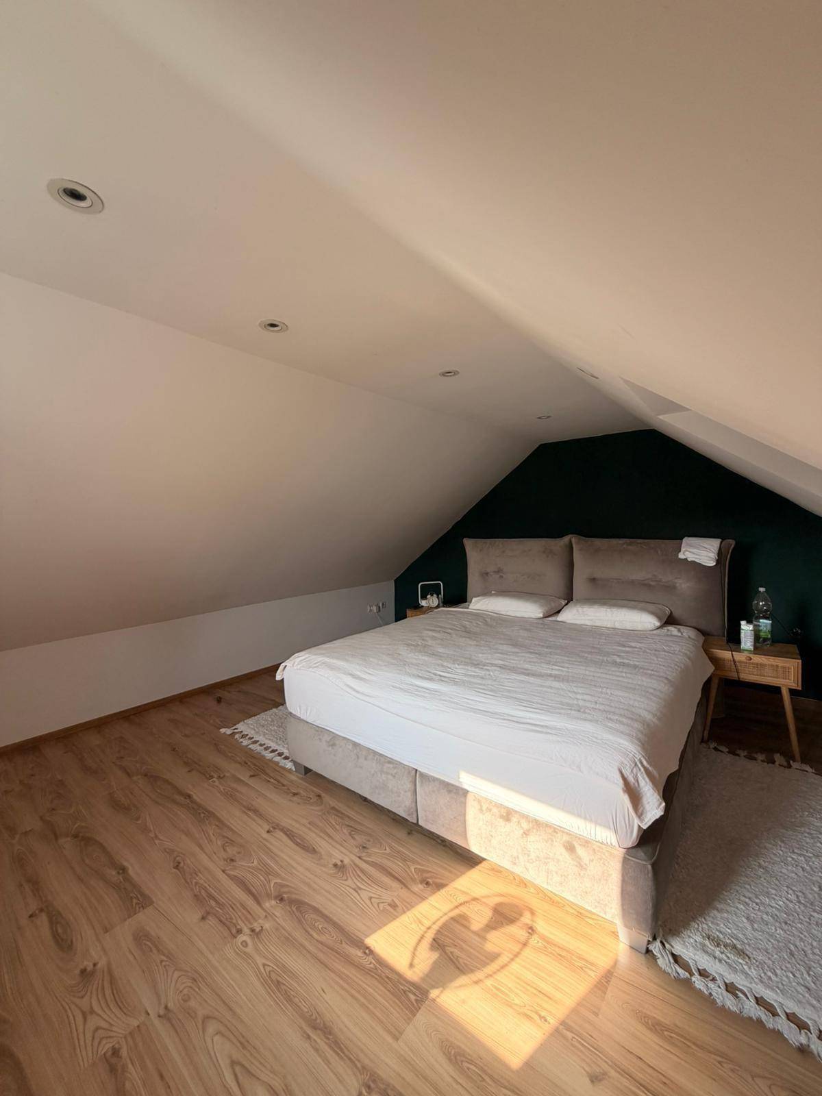 Helles Schlafzimmer im Dachgeschoss mit Holzboden, Dachschräge und Doppelbett.