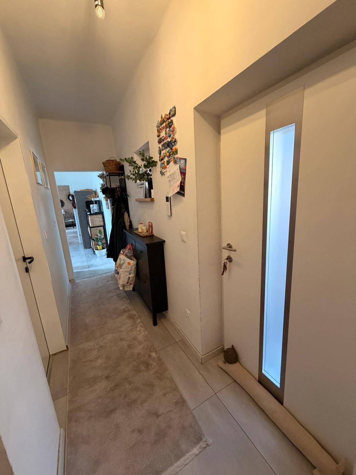 Heller Eingangsbereich mit Fliesenboden, Garderobe und langer Diele.