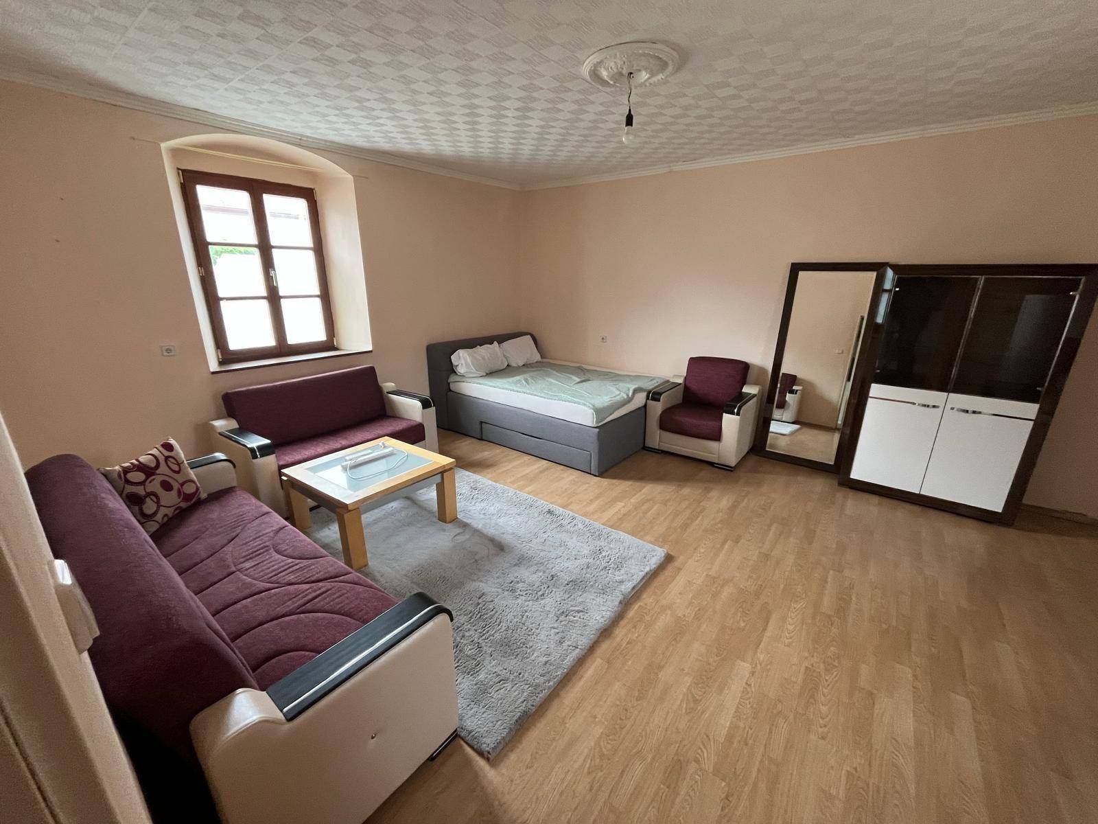 Geräumiger Raum mit Holzboden, zwei Sofas und einem Bett.