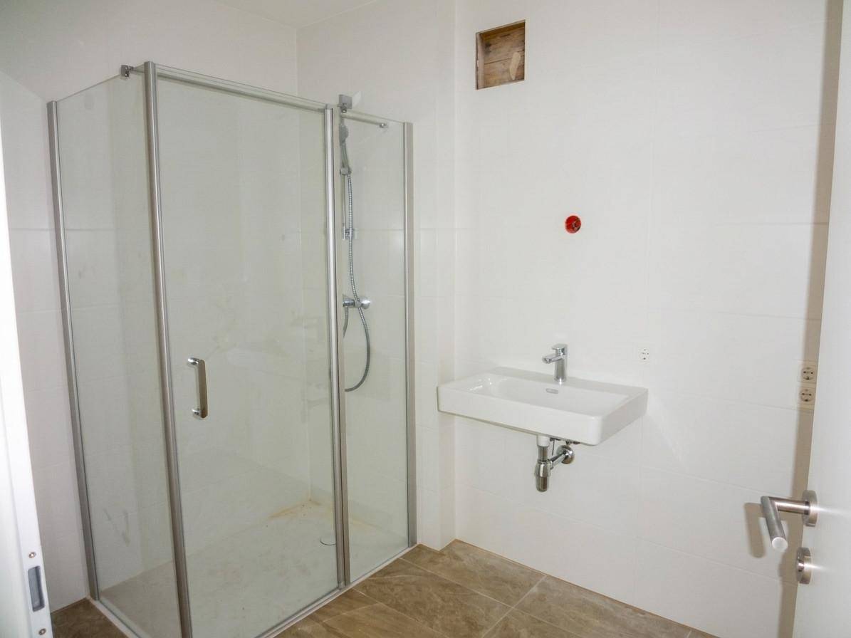 Badezimmer im Bau mit Duschkabine und Waschbecken, bereit für die Fertigstellung.