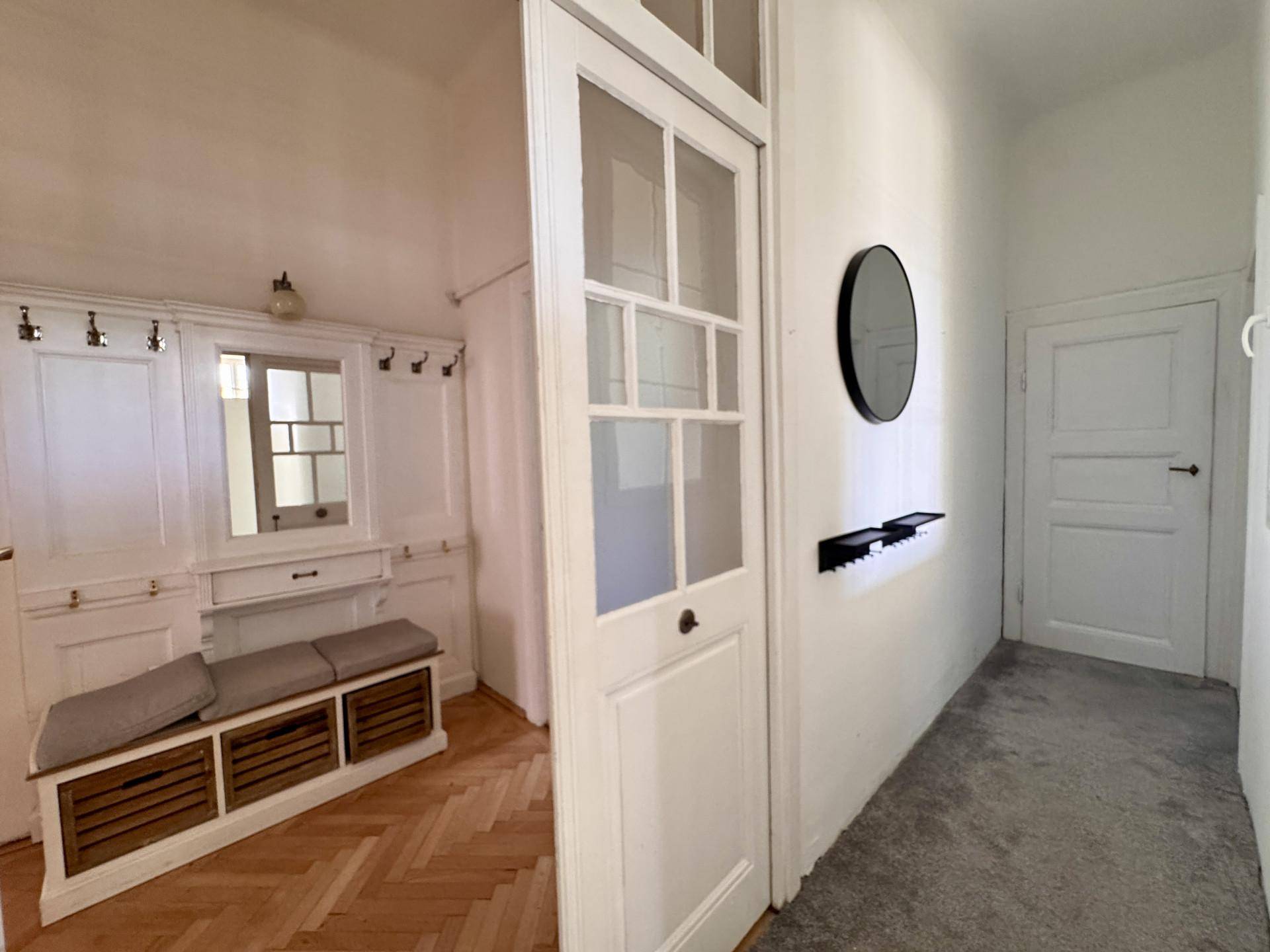 Heller Flur mit integrierter Garderobe, Sitzbank und klassischem Fischgrätparkettboden.