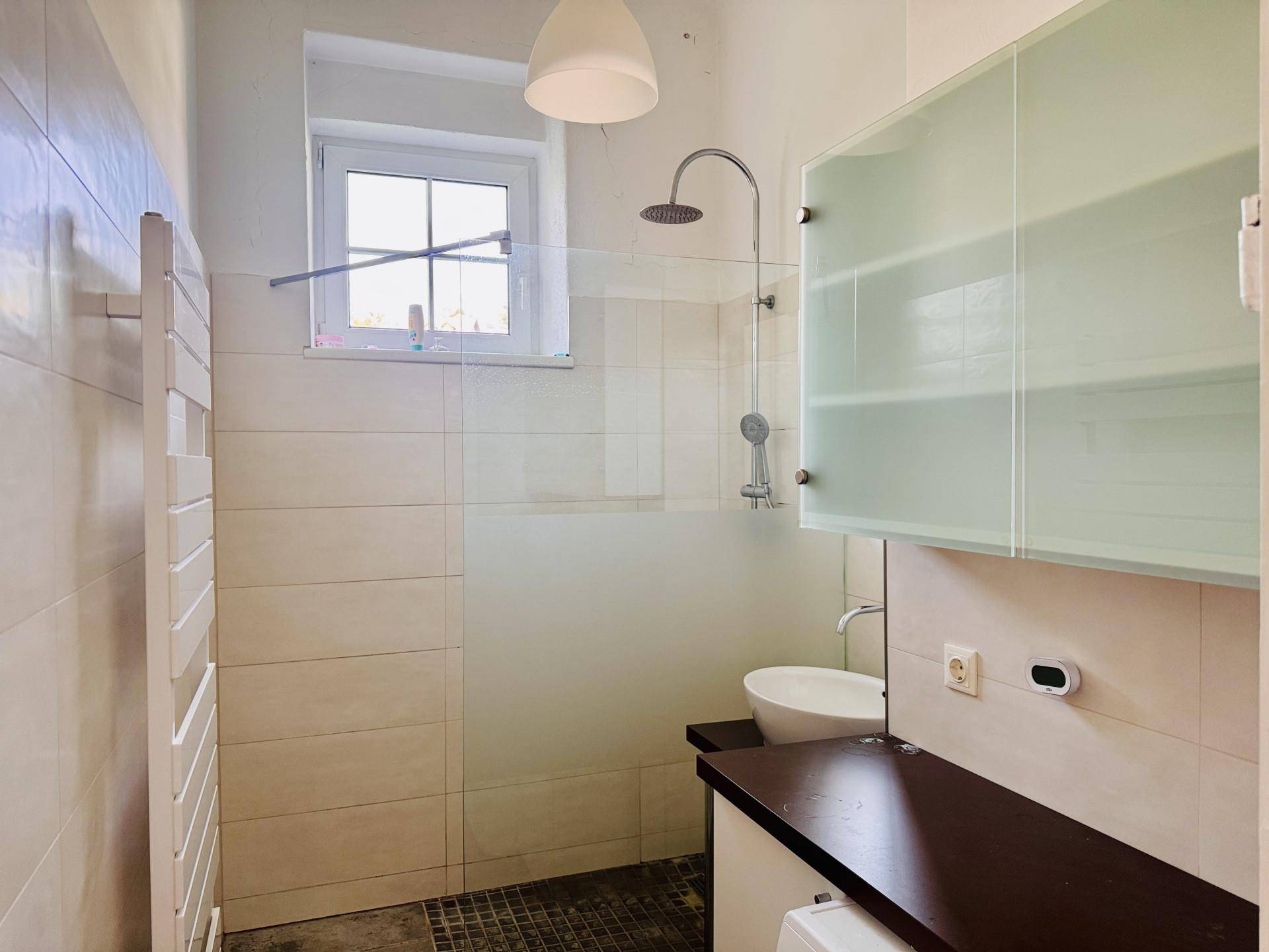 Modernes Badezimmer mit ebenerdiger Dusche, weißen Fliesen und beheiztem Handtuchhalter.