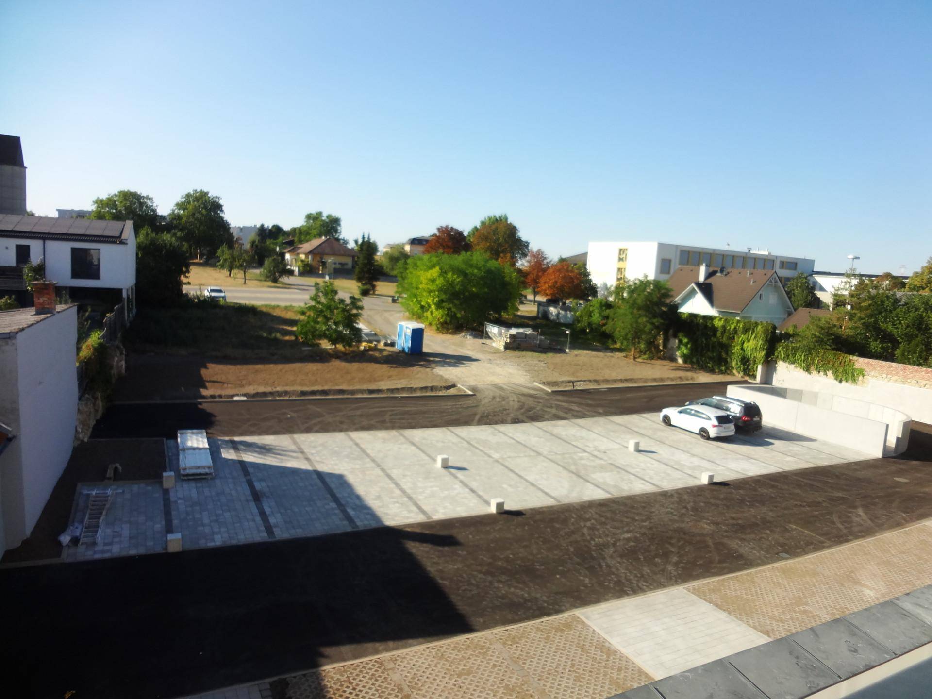 Weitläufiger Blick von einem Balkon auf den Parkplatz und die Umgebung.