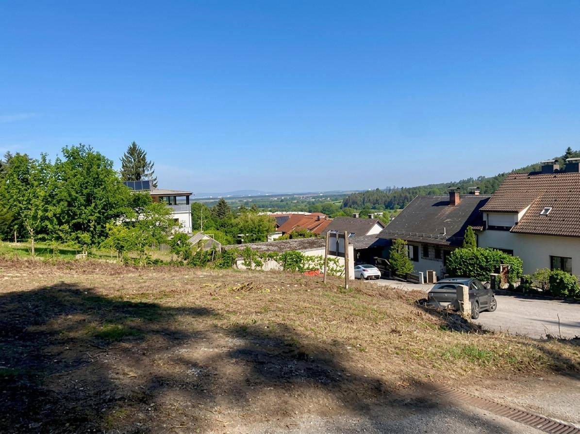 Grundstück mit Fernblick über eine weite Ebene und angrenzende Wohnhäuser.