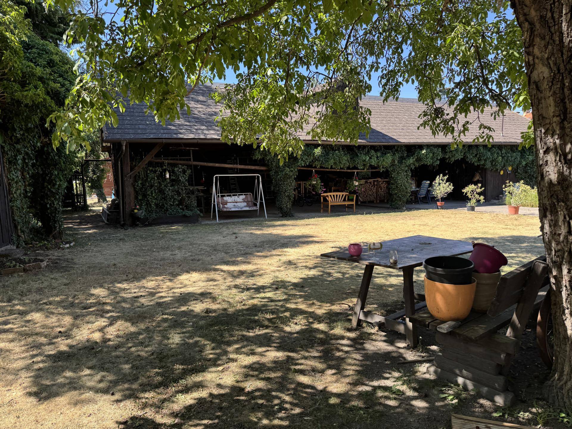 Großer Garten mit Rasenfläche, Schaukel und einer rustikalen Scheune im Hintergrund.