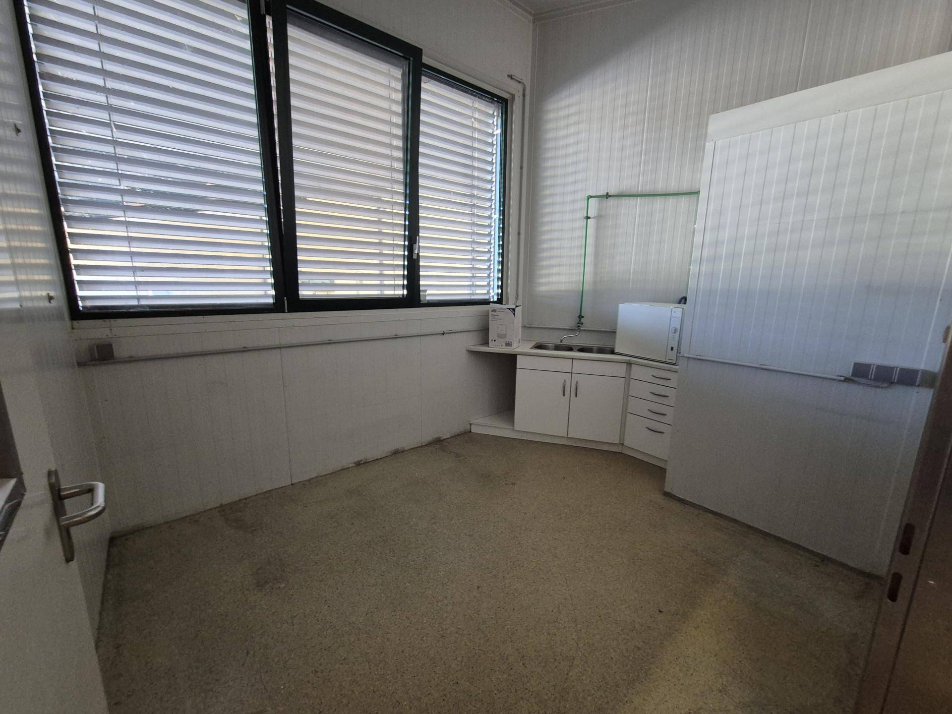 Kleiner Raum mit Spülbecken, Unterschränken und einem Fenster mit Jalousien.