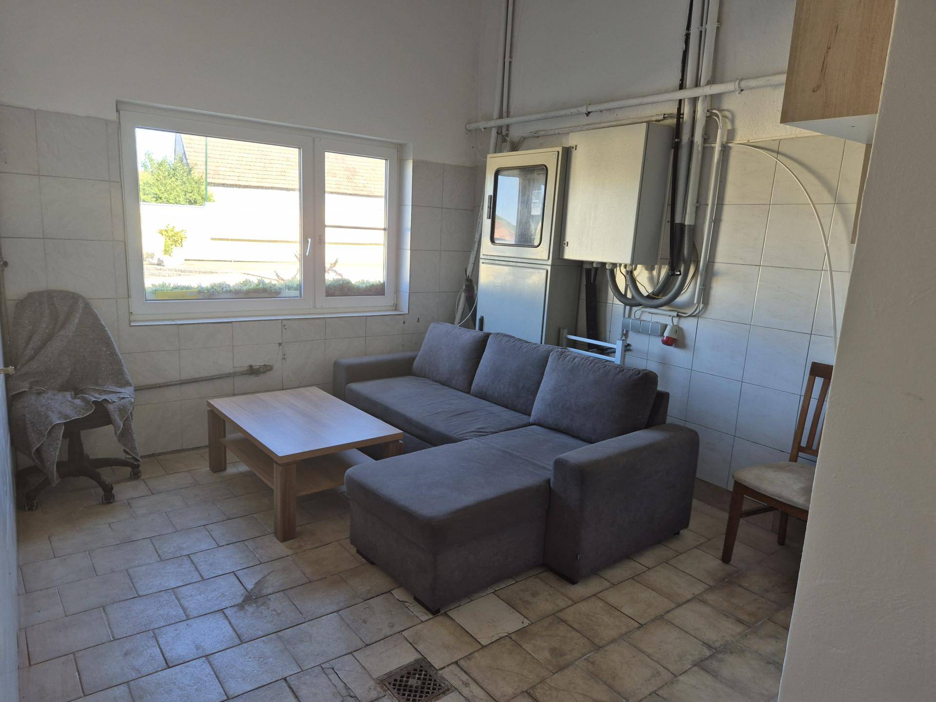 Kleiner Raum mit Fliesenboden und -wänden, ausgestattet mit Sofa und Kaffeetisch, daneben elektrische Installationen.