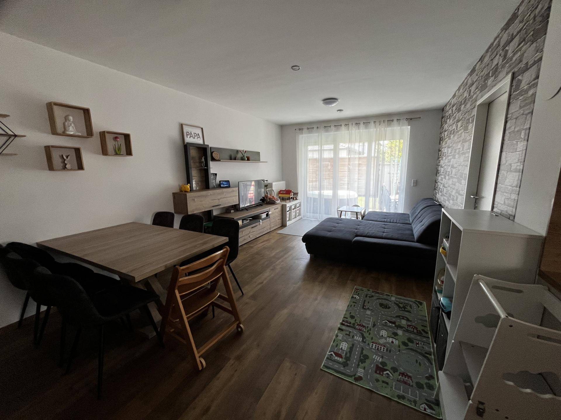 Heller Wohn- und Essbereich mit großem Fenster, Sofa und Esstisch für die Familie.