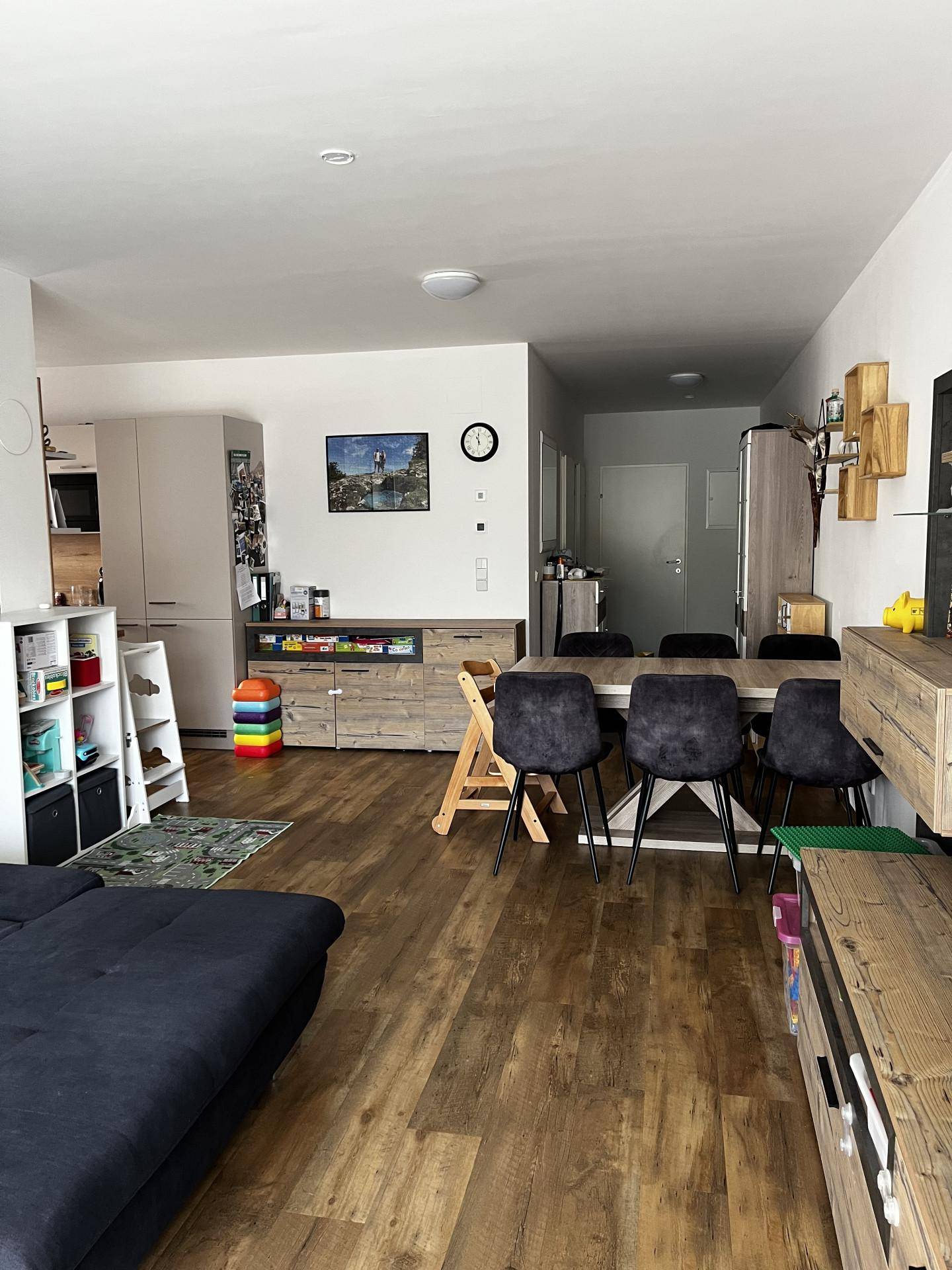 Offener Wohnbereich mit Esstisch, Sofa und Blick auf den Eingangsbereich und die Küche.
