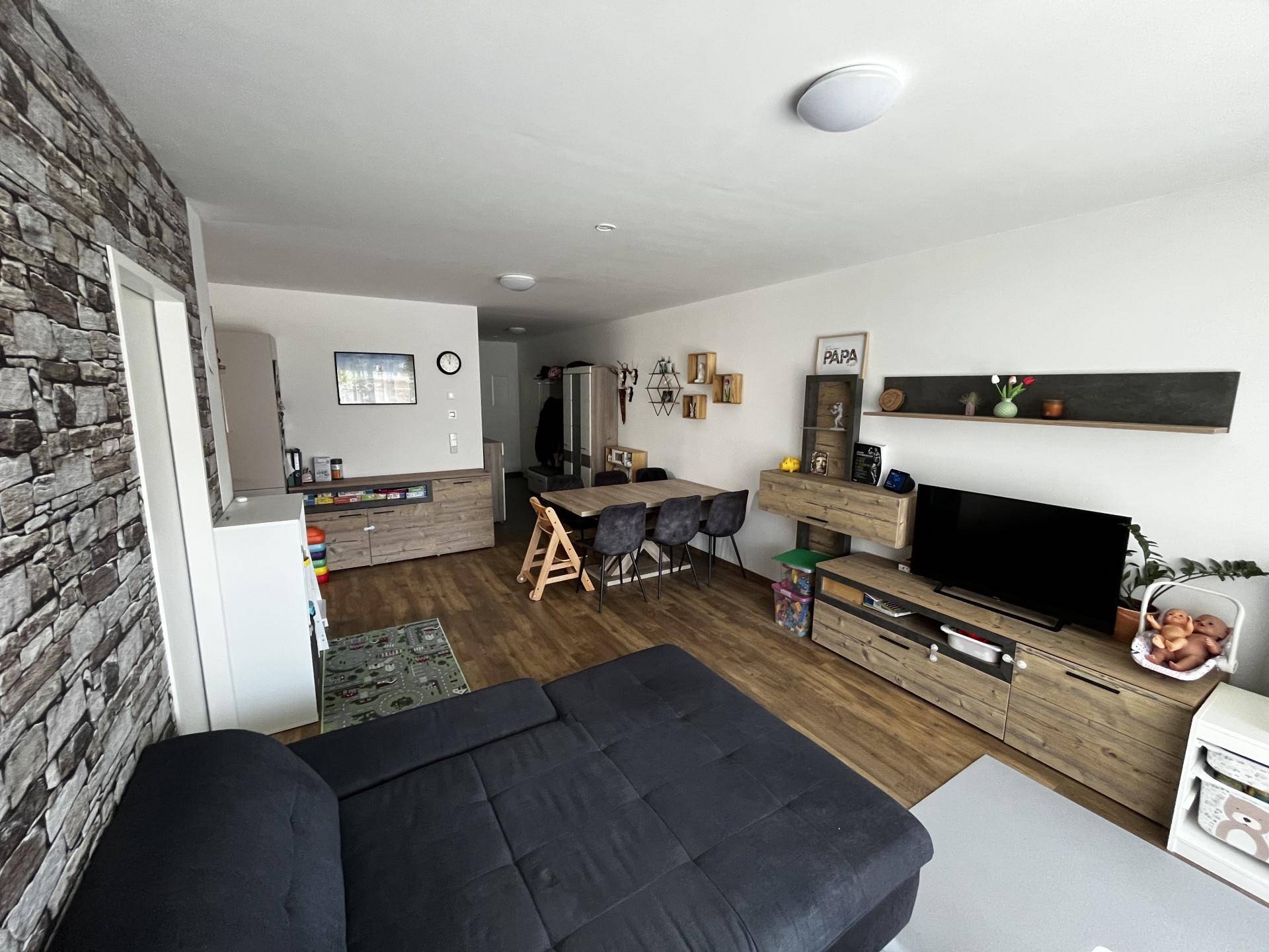 Geräumiger Wohn- und Essbereich mit Sofa, Esstisch und Steinwand-Akzent für modernes Wohnen.