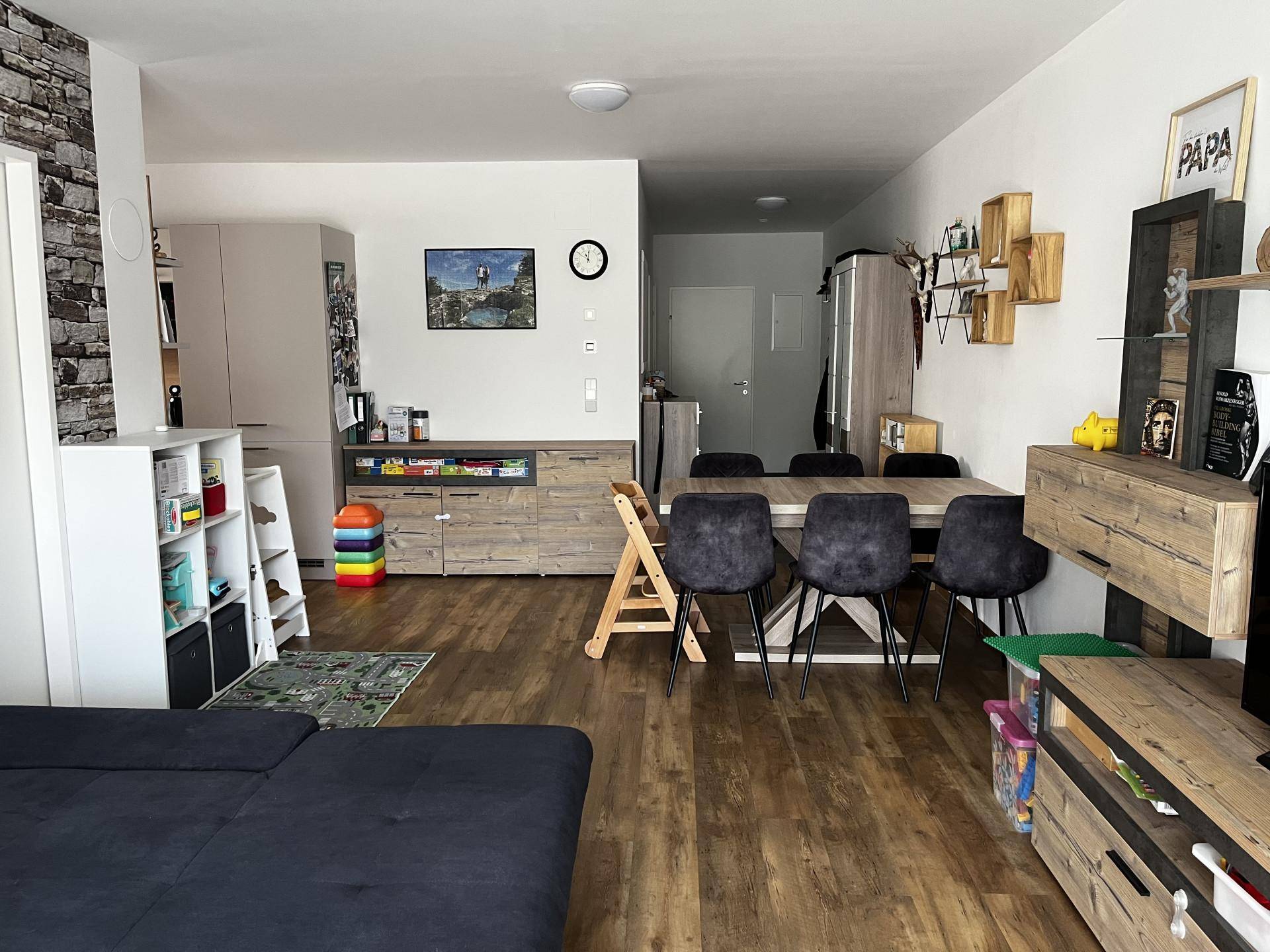 Heller Wohn- und Essbereich mit Esstisch, Sofa und modernem Dekor in warmen Holztönen.
