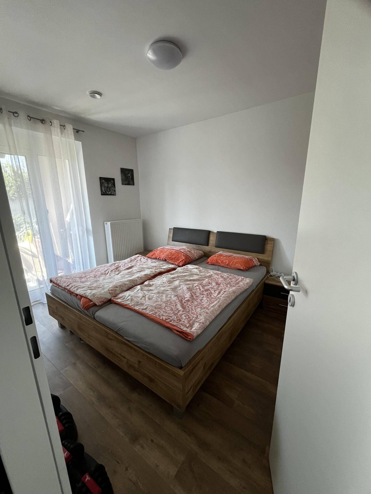 Schlafzimmer mit Doppelbett, Holzboden und Zugang zu einem Balkon oder einer Terrasse.