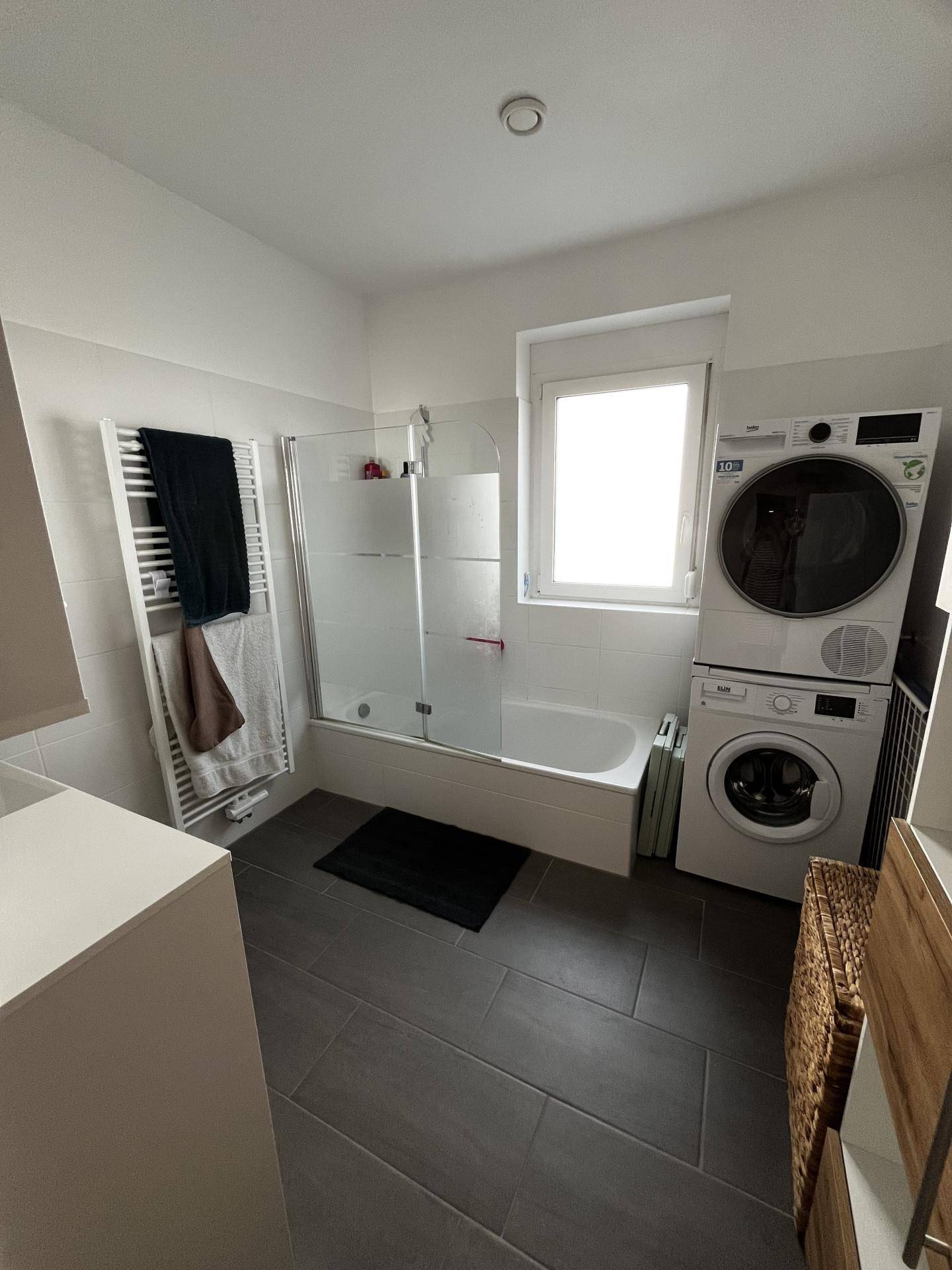 Modernes Badezimmer mit Badewanne, Dusche, Waschmaschine und Trockner.