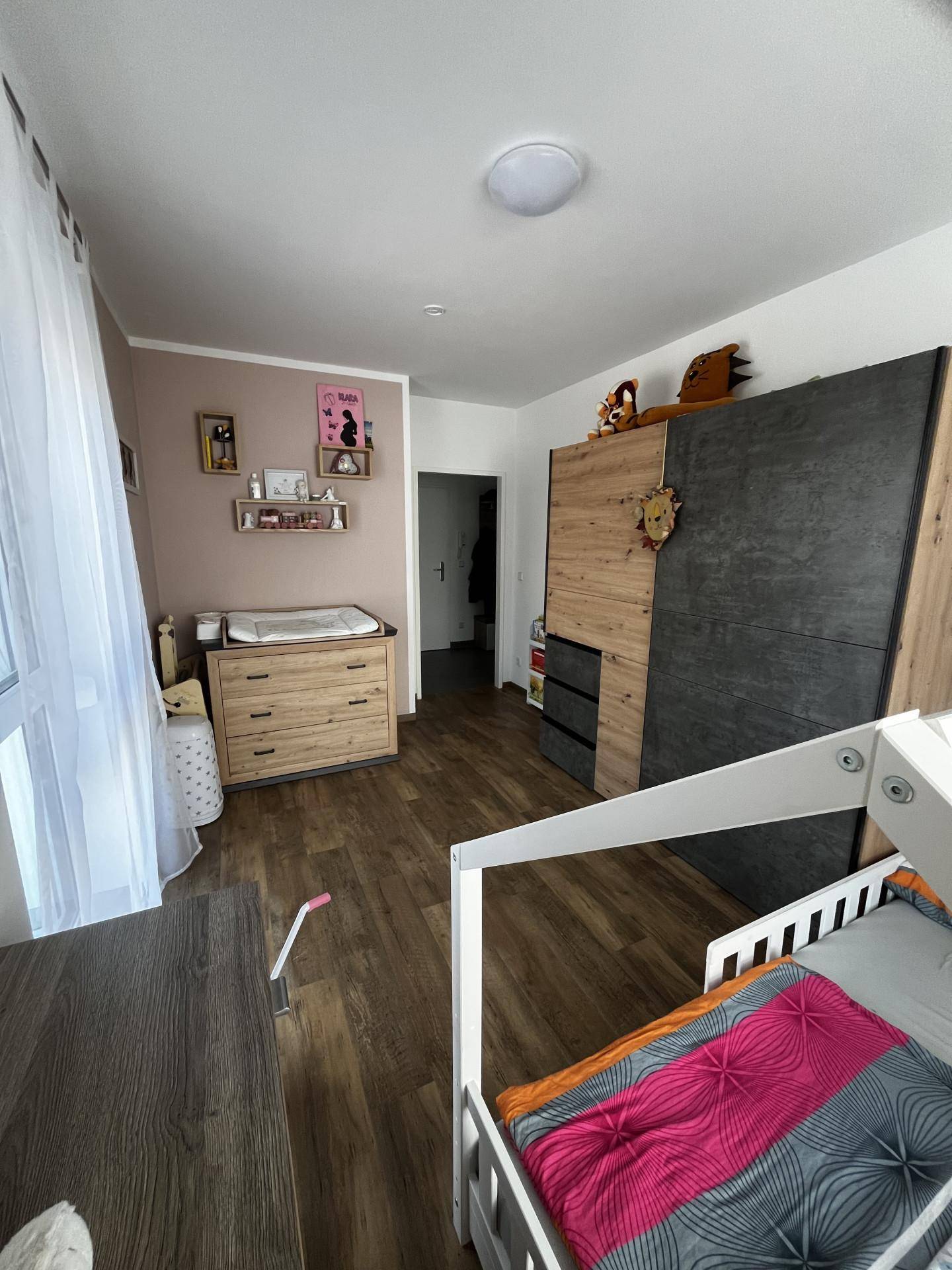 Kinderzimmer mit Wickelkommode, Schrank und Holzboden, hell und freundlich gestaltet.