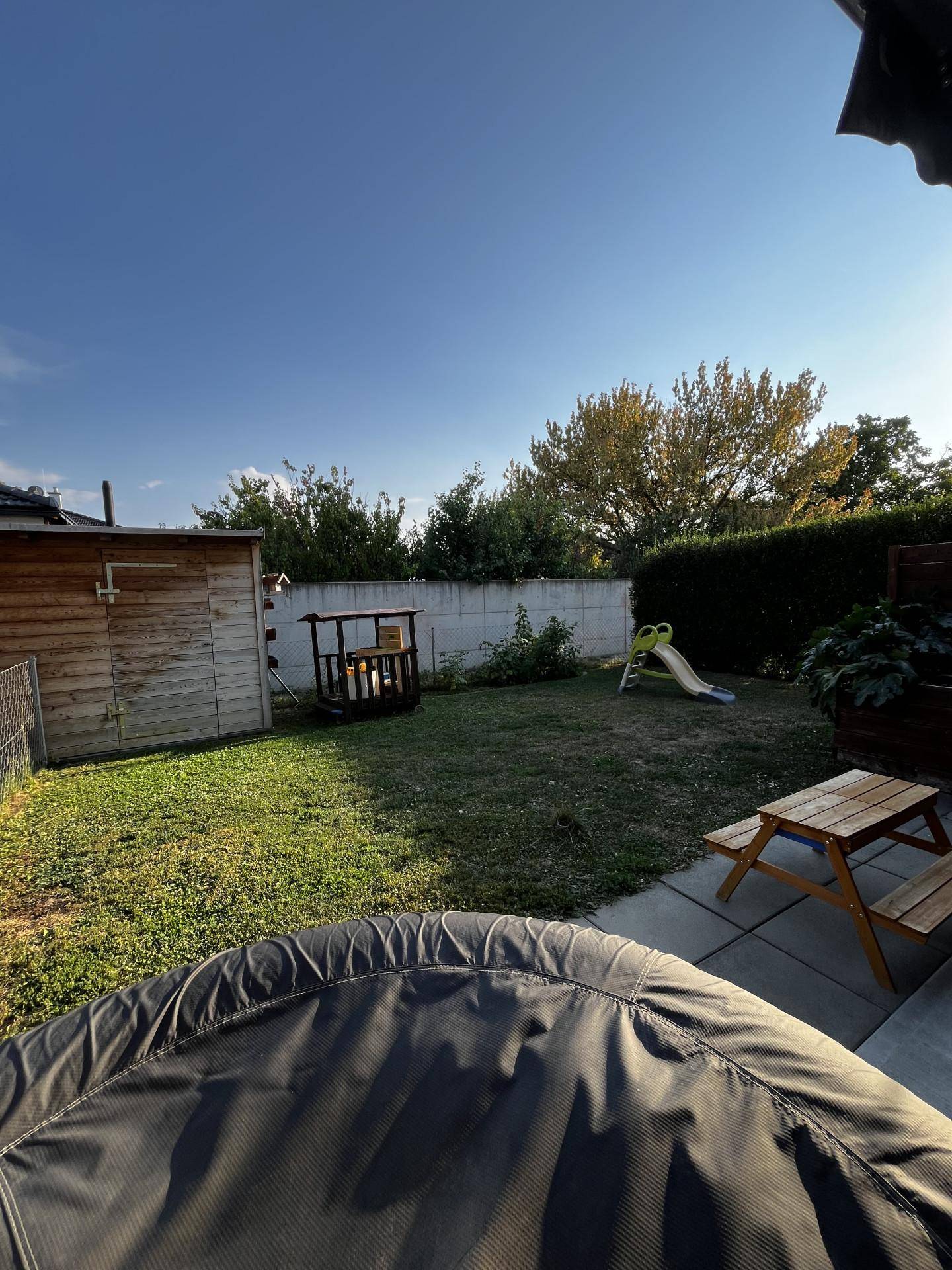 Gepflegter Gartenbereich mit Rasenfläche, Kinderspielgeräten und Sitzgelegenheiten für die Familie.