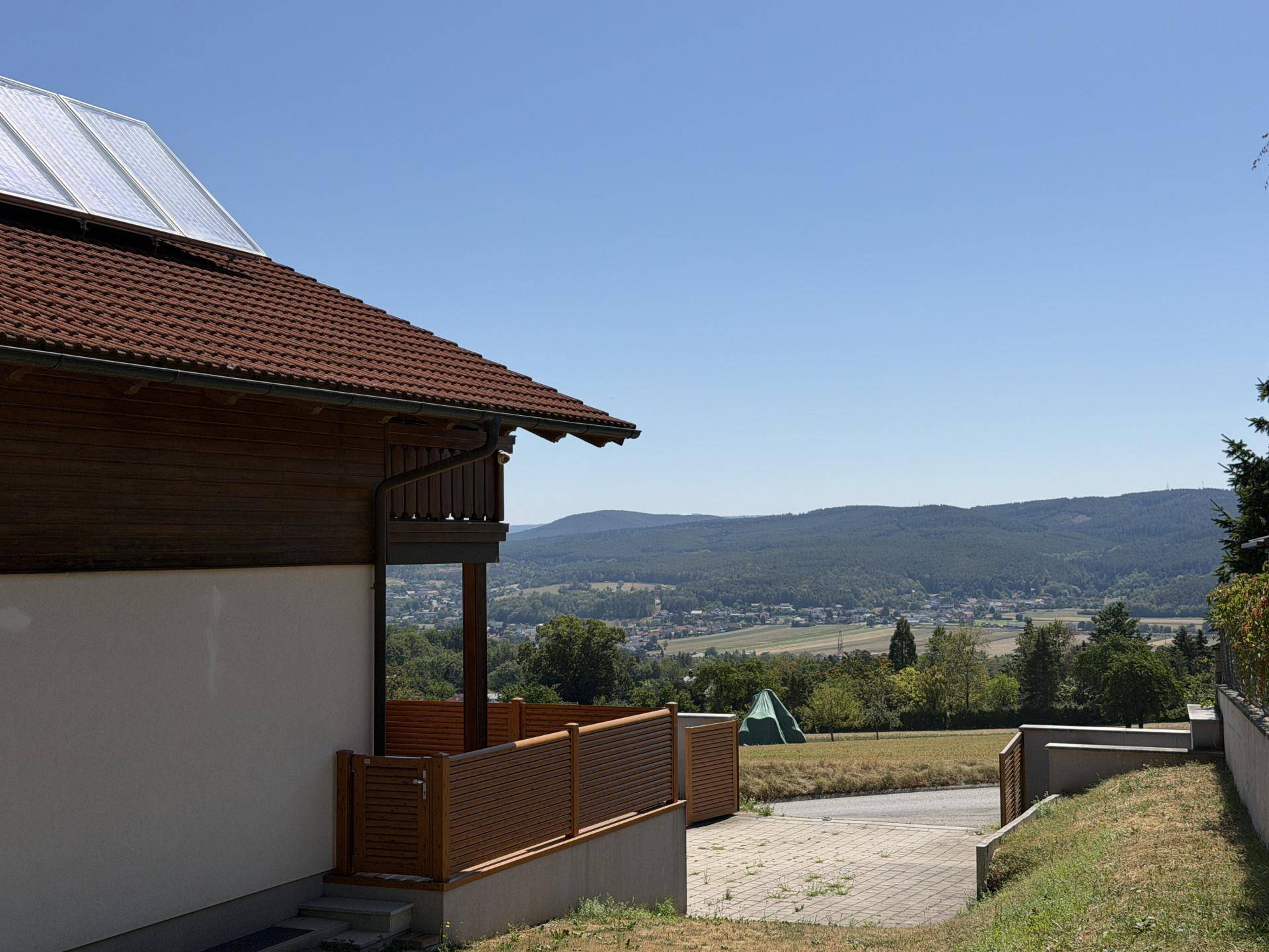 Seitenansicht des Hauses mit Solaranlage auf dem Dach und weitem Landschaftsblick.