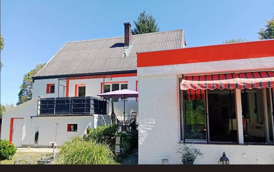 Detailansicht der oberen Terrasse mit Sonnenschirm und Blick auf das Dach des Hauses.