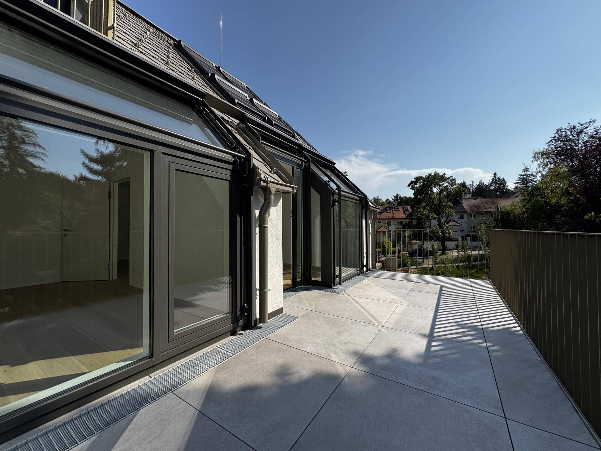 Breite Terrasse mit Zugang zu den Innenräumen und Blick auf die umliegende Wohngegend.