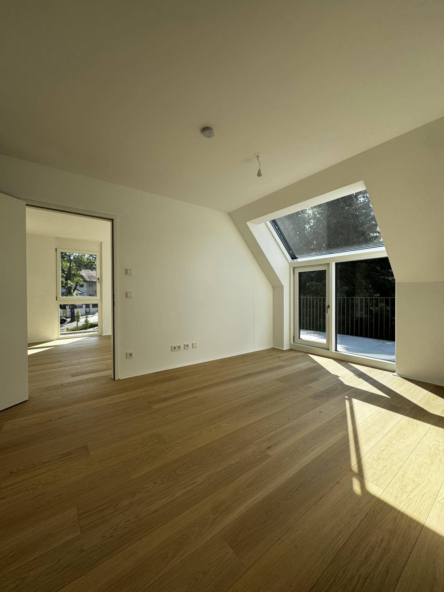 Geräumiges Schlafzimmer mit hellem Parkettboden und schrägen Dachfenstern für viel Tageslicht.