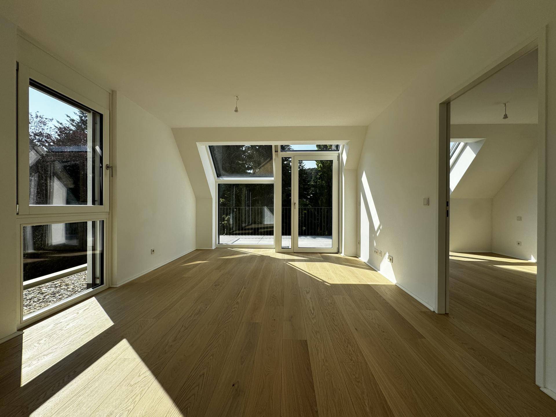 Helles Schlafzimmer im Dachgeschoss mit Holzboden und großen Fenstern, die viel Licht spenden.
