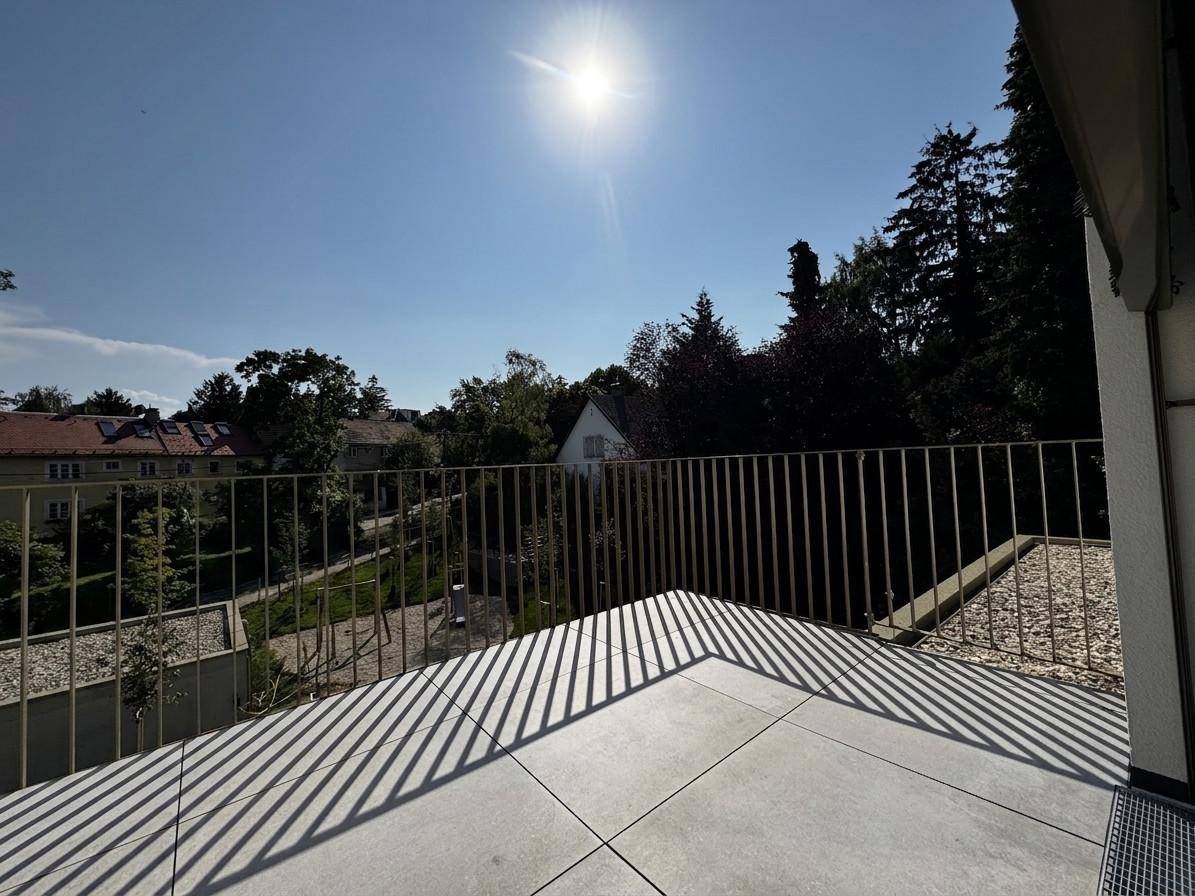 Sonniger Terrassenbereich mit modernem Geländer und weitem Blick über die grüne Umgebung.