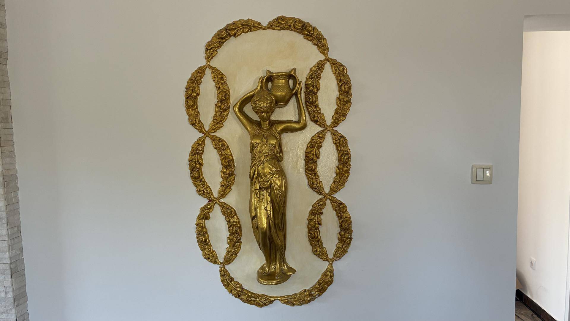 Detailansicht einer opulenten goldenen Wanddekoration in einem Innenraum.